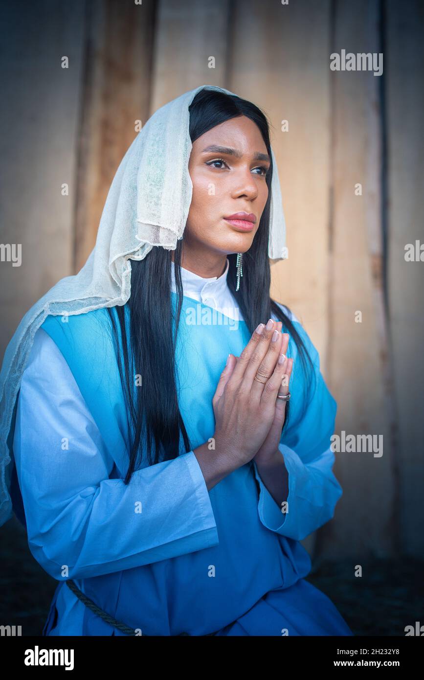 Transsexuelle Jungfrau, die mit ihrem verlorenen Blick betet Stockfoto