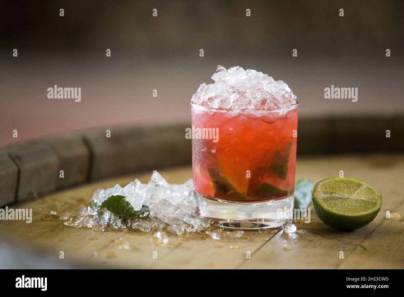 Nahaufnahme eines Glases roten Alkoholcocktails auf einem Holzfass Stockfoto