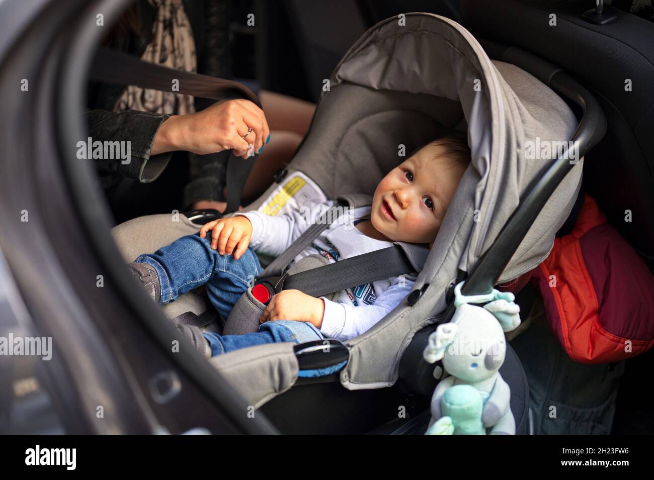 Netter kleiner Junge, der in einem Auto auf seinem Stuhl sitzt Stockfoto