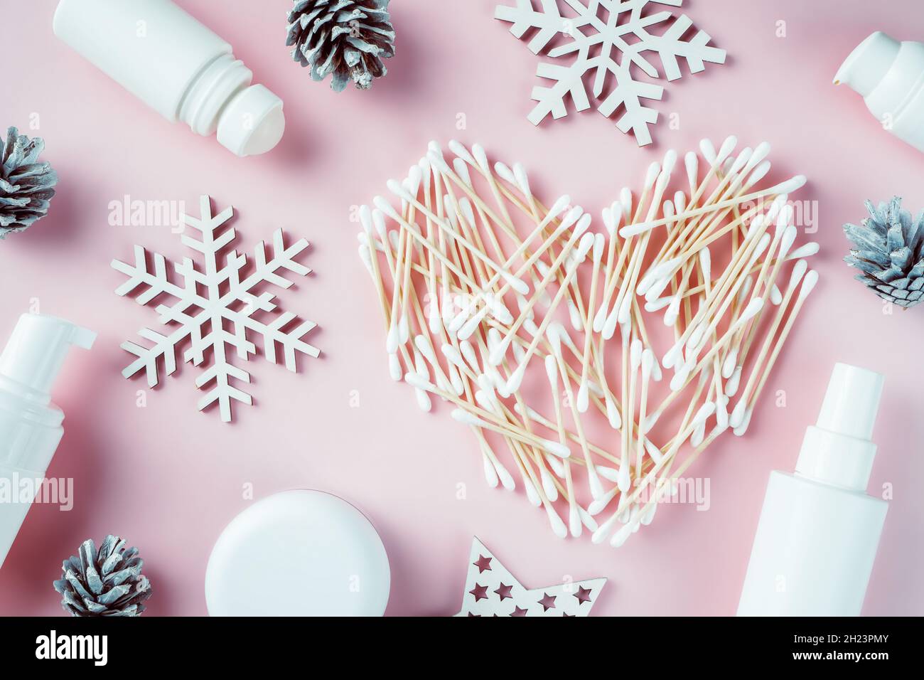 Herzförmige Wattestäbchen aus Holz mit Schneeflocken aus Holz,  Tannenzapfen, Kosmetikgläsern und Deodorant auf rosa Hintergrund. Flach  liegend Stockfotografie - Alamy
