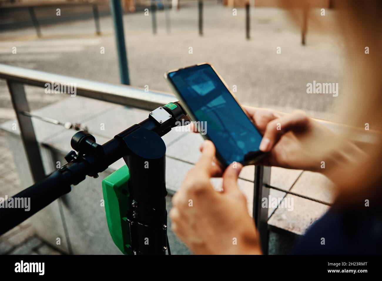 Frau entsperren Elektroroller zur Miete mit Handy-App. Moderner städtischer Ökotransport Stockfoto