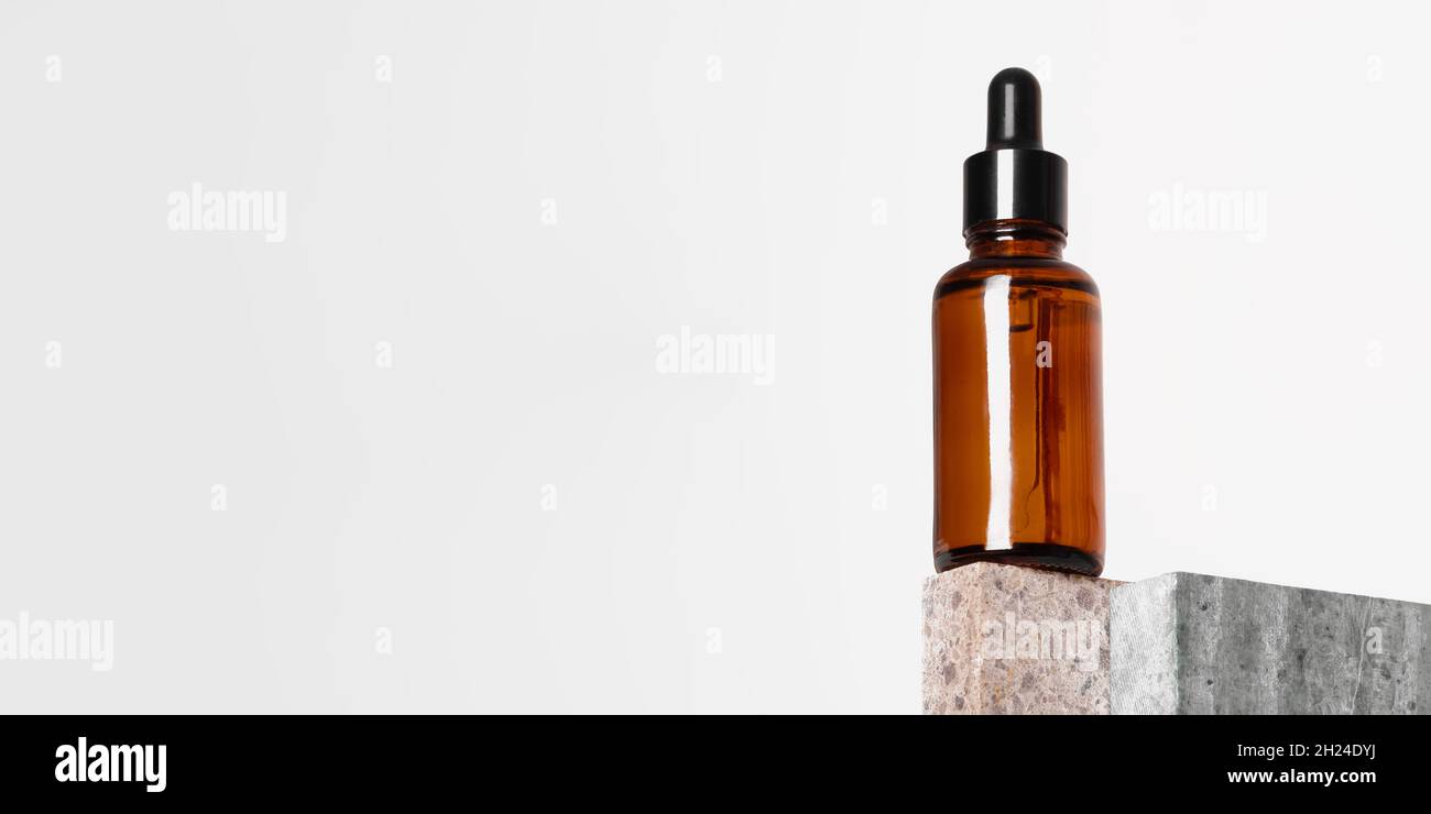 Braunglas Tropfflasche mit einer Pipette auf einem Stück Stein. Naturkosmetik-Konzept, natürliches ätherisches Öl. Stockfoto