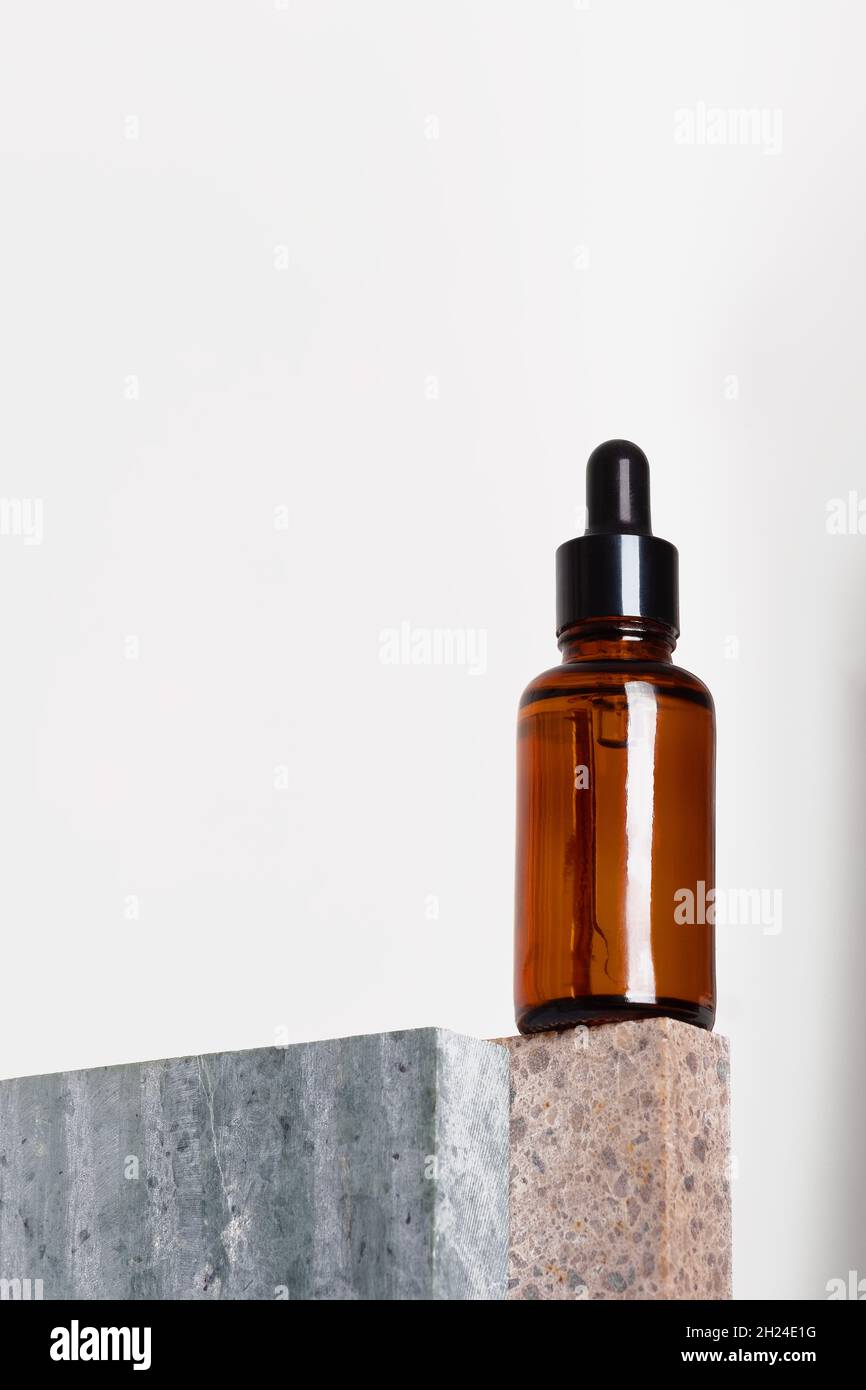 Braunglas Tropfflasche mit einer Pipette auf einem Stück Stein. Naturkosmetik-Konzept, natürliches ätherisches Öl. Stockfoto