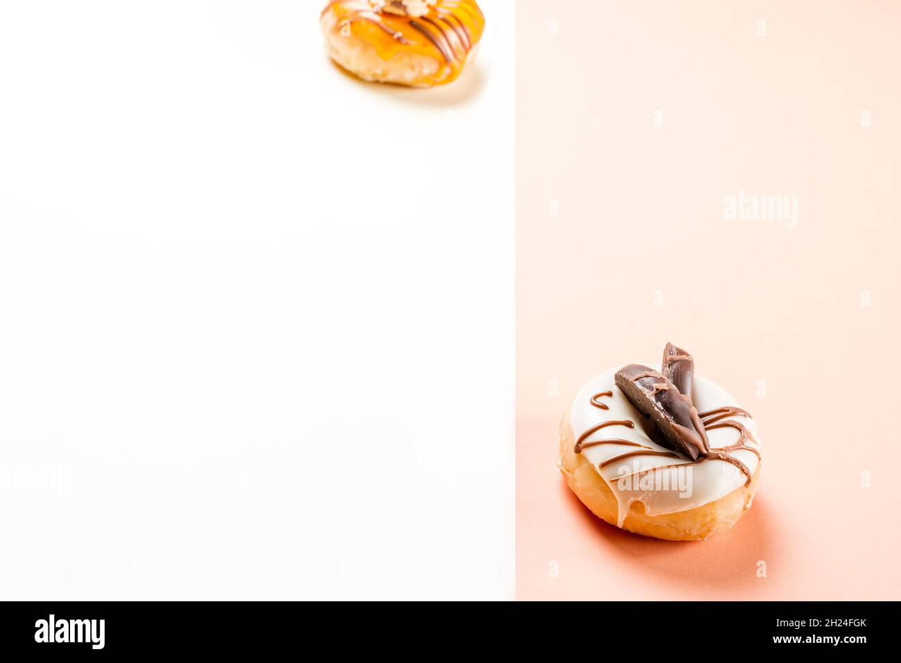 Nahaufnahme eines weißen Donuts mit Schokoladenkeksen und einer Seite von unfokussierten Creme-Donuts.das Foto ist im horizontalen Format aufgenommen und hat zwei Stockfoto