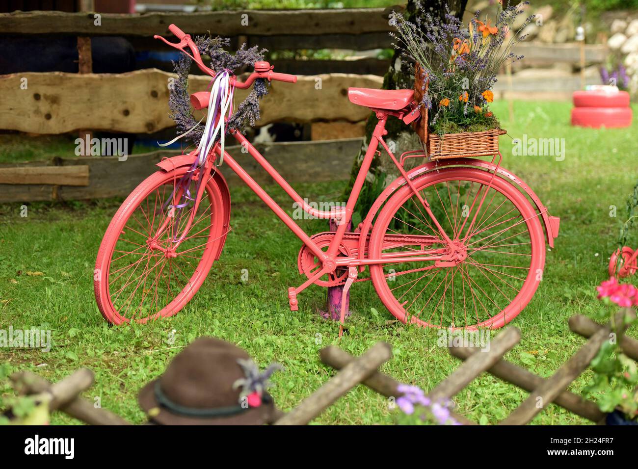 Rosa angestricktes Fahrrad mit Blumenschmuck im Salzkammergut, Österreich, Europa - Rosa lackiertes Fahrrad mit Blumenstrauß im Salzkammergut, Au Stockfoto