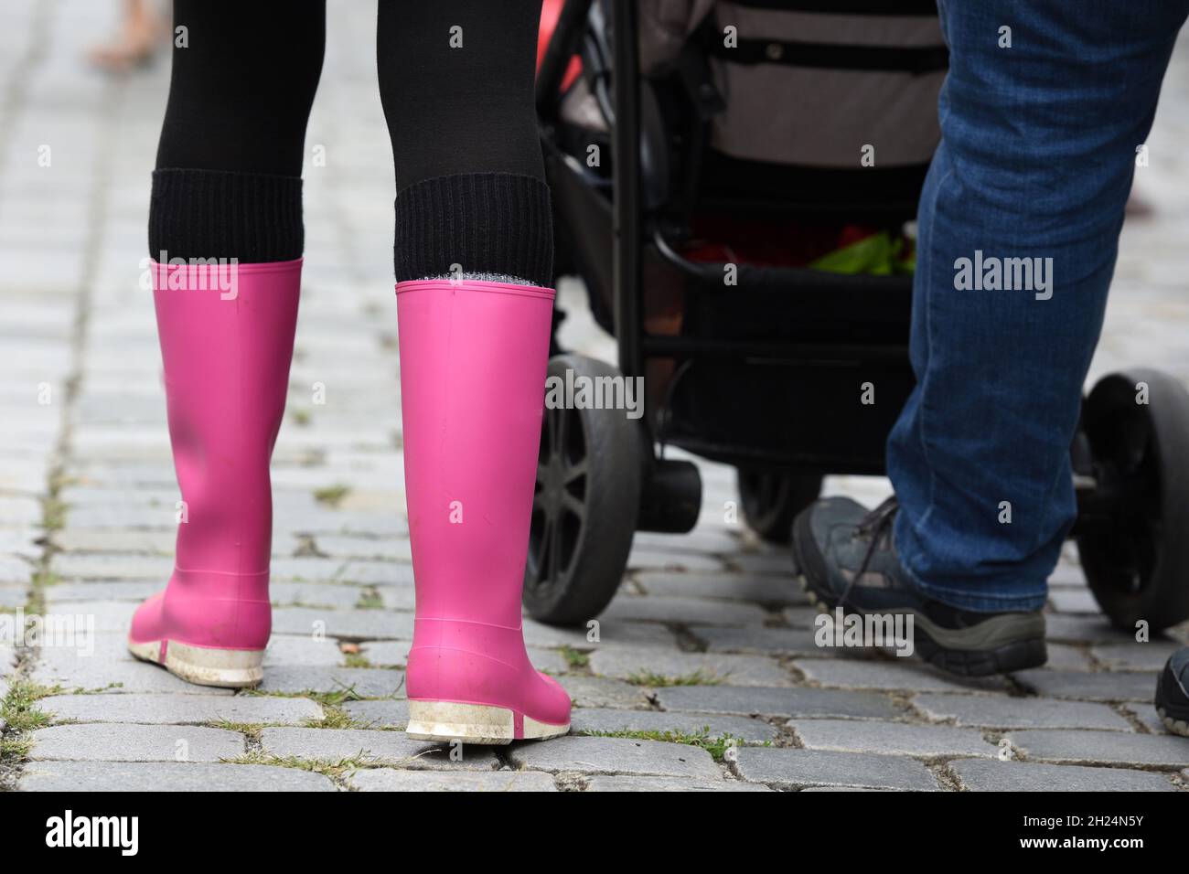 Junge Frau mit rosa Gummistiefel geht auf einer Straße - Junge Frau mit rosa Gummistiefeln geht auf einer Straße Stockfoto