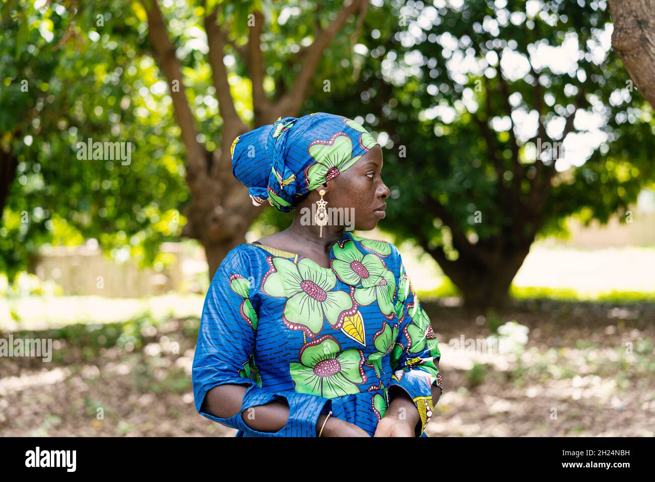 Schöne schwarze afrikanische Dorfbewohner in einem farbenfrohen traditionellen Kleid mit passender Kopfbedeckung Stockfoto