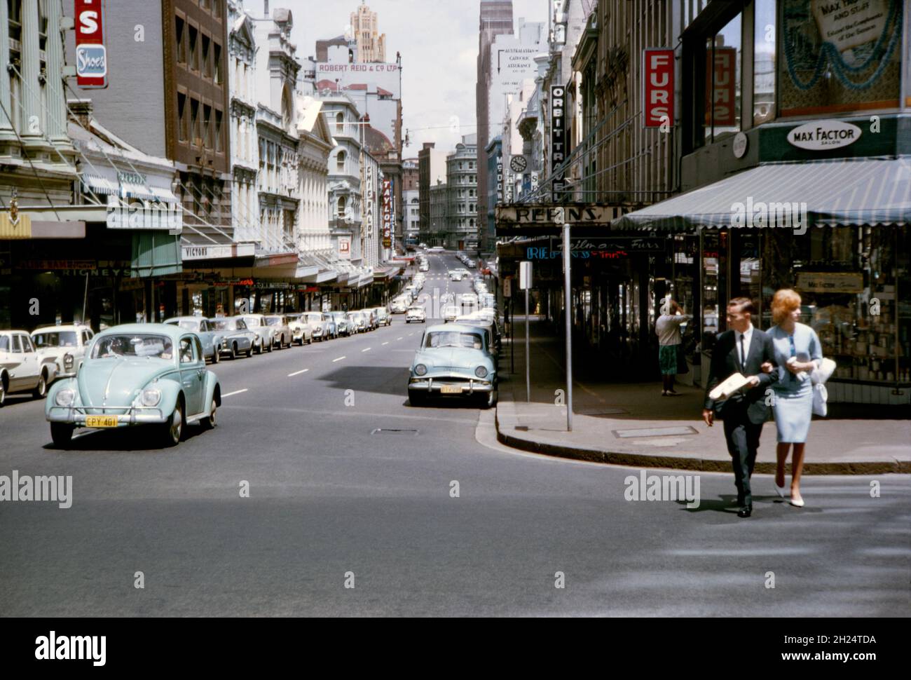 Ein Blick nach Westen auf die King Street, Sydney, NSW, Australien im Jahr 1964 von der Kreuzung mit der Castlereagh Street. Die normalerweise geschäftige Straße scheint sehr ruhig zu sein, so dass es durchaus ein Sonntag sein könnte. Die Gegend ist sehr verändert und alle Geschäfte rechts sind nun weg, ersetzt durch den Turm und den Einkaufskomplex des MLC Centers. Die King Street ist eine Straße im Stadtzentrum von Sydney. Dieses Bild stammt von einem alten Kodak-Amateurfotograf mit Farbtransparenz – einem alten Foto aus den 1960er Jahren. Stockfoto