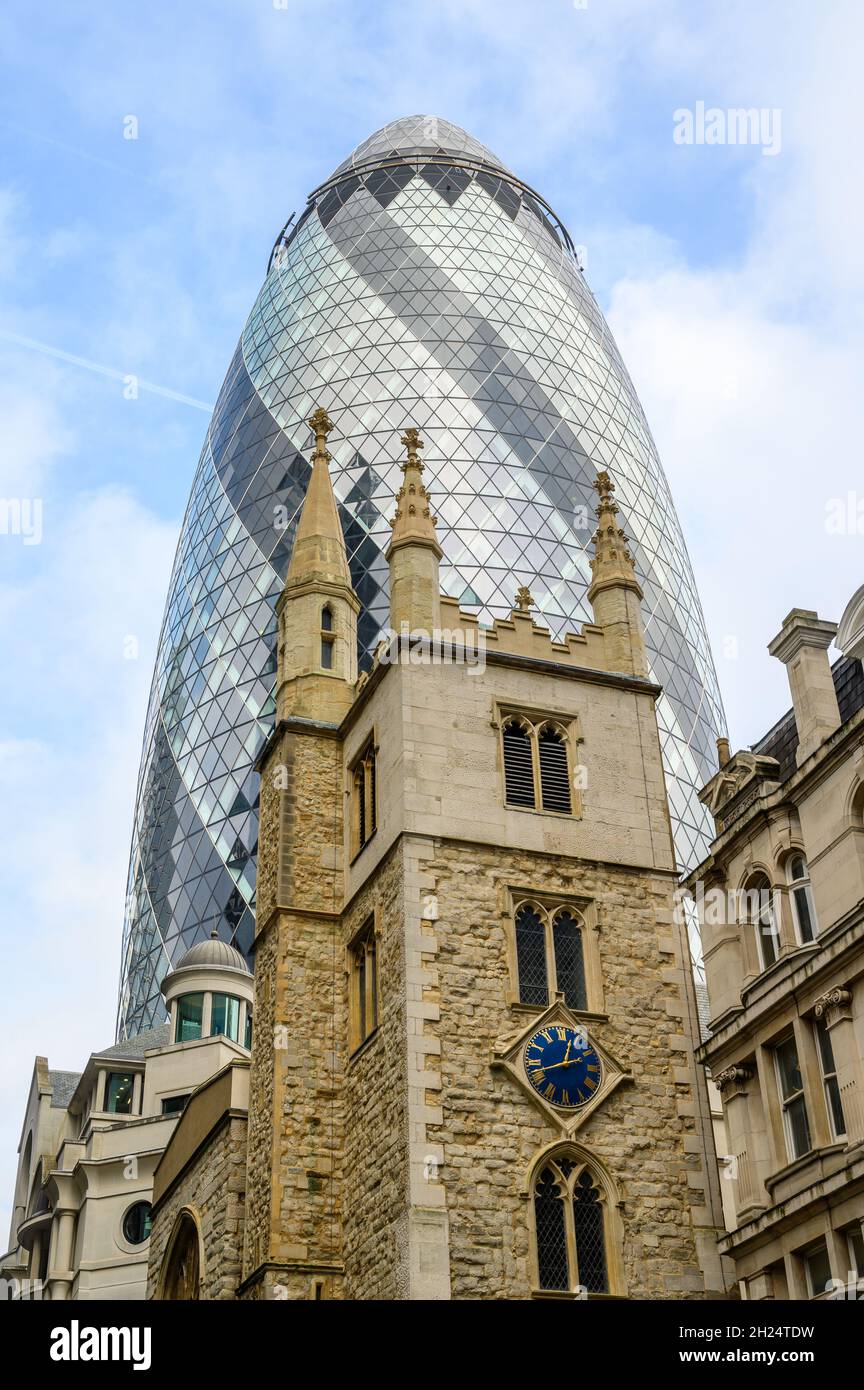 Alt und neu: Die St. Andrew Undershhaft Church aus dem 15. Jahrhundert vor dem Gherkin-Bürogebäude aus dem Jahr 2004 in der City of London, England. Stockfoto