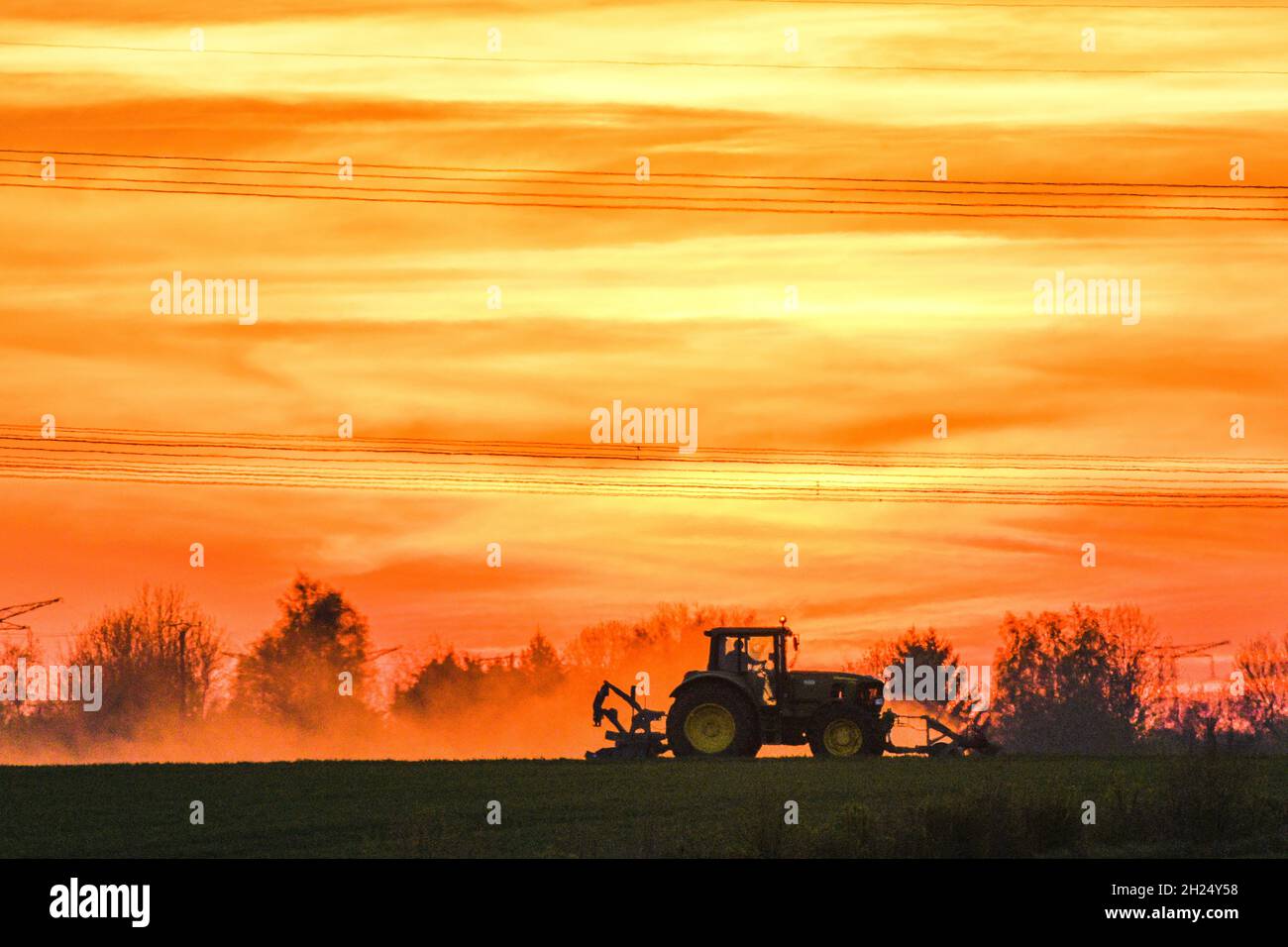Landwirtschaftliche Arbeiten bei Sonnenuntergang. Traktor auf einem Feld Stockfoto