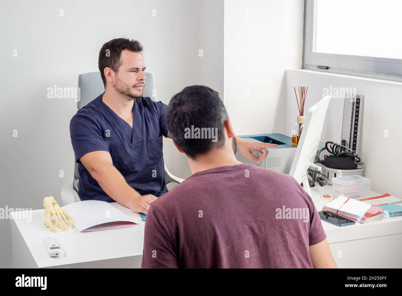 Physiotherapeut erklärt die Entwicklung eines Patienten auf einem Computerbildschirm. Stockfoto
