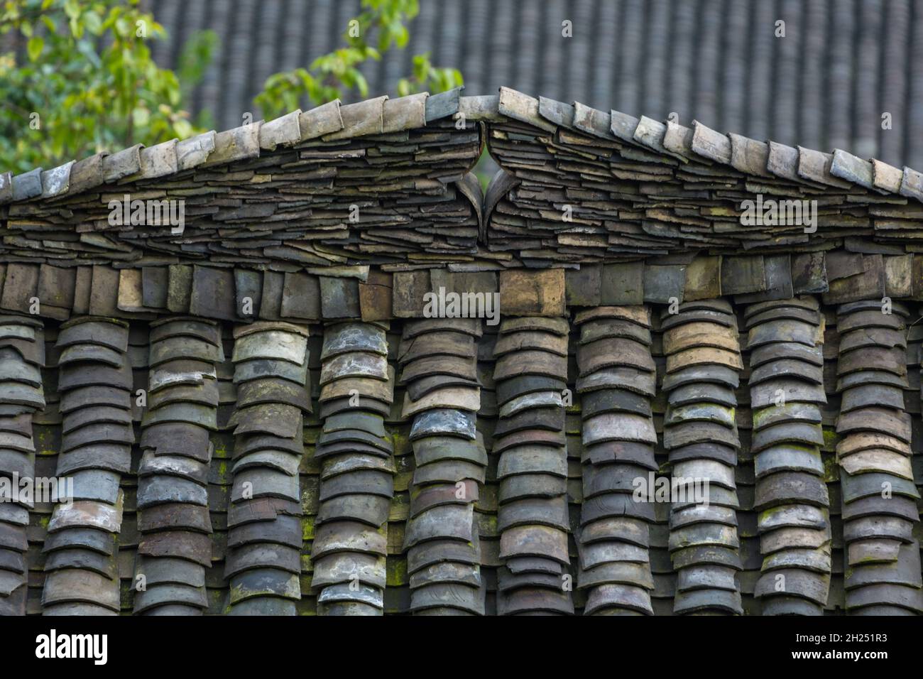 Ein dekoratives Design in den Tonfliesen auf dem Dachkamm oa ein traditionelles Bauernhaus in Longshen, China. Stockfoto
