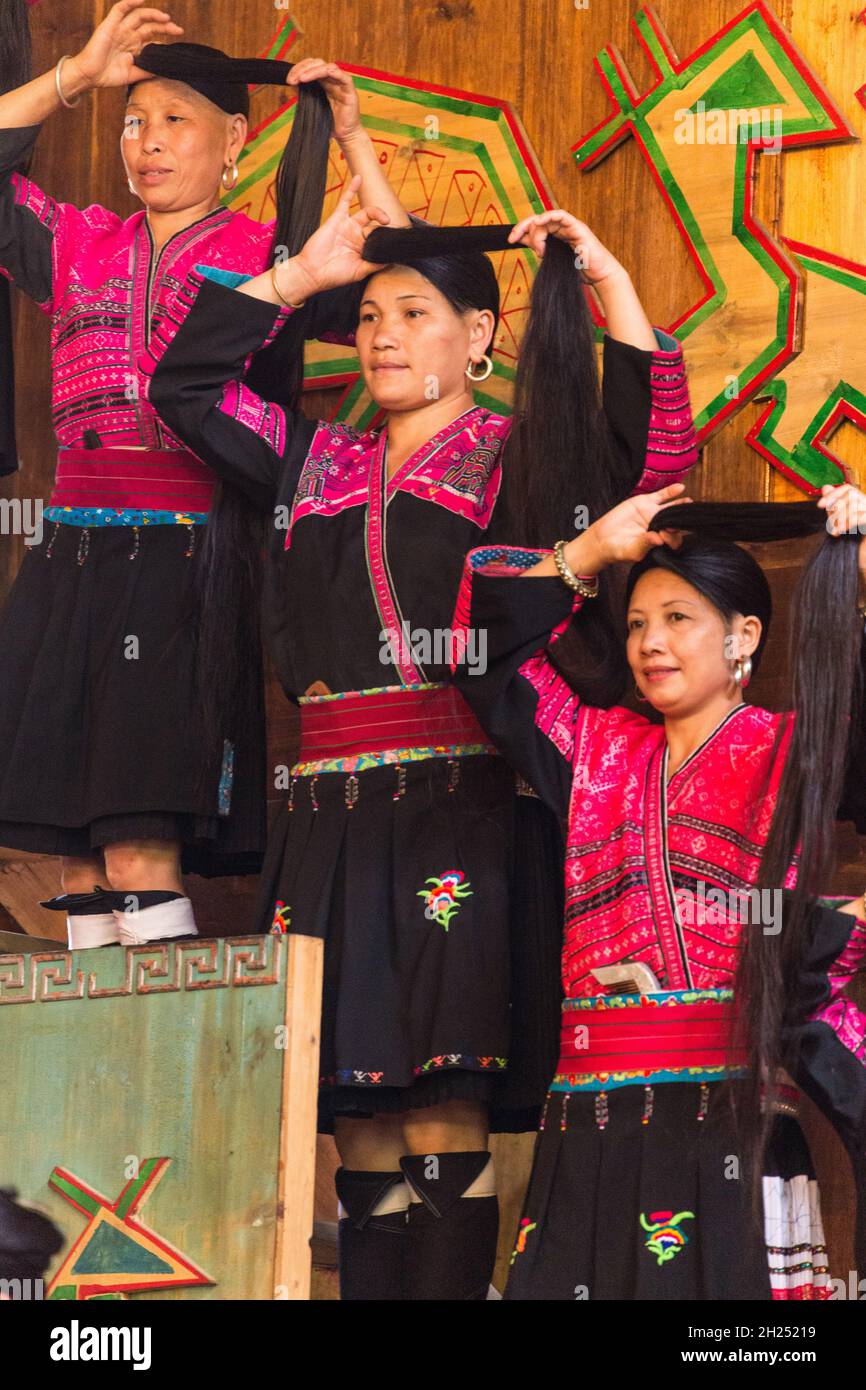 Eine Frau aus der ethnischen Minderheit der roten Yao zeigt, wie sie ihre traditionellen langen Haare fixieren. Huangluo, China. Stockfoto