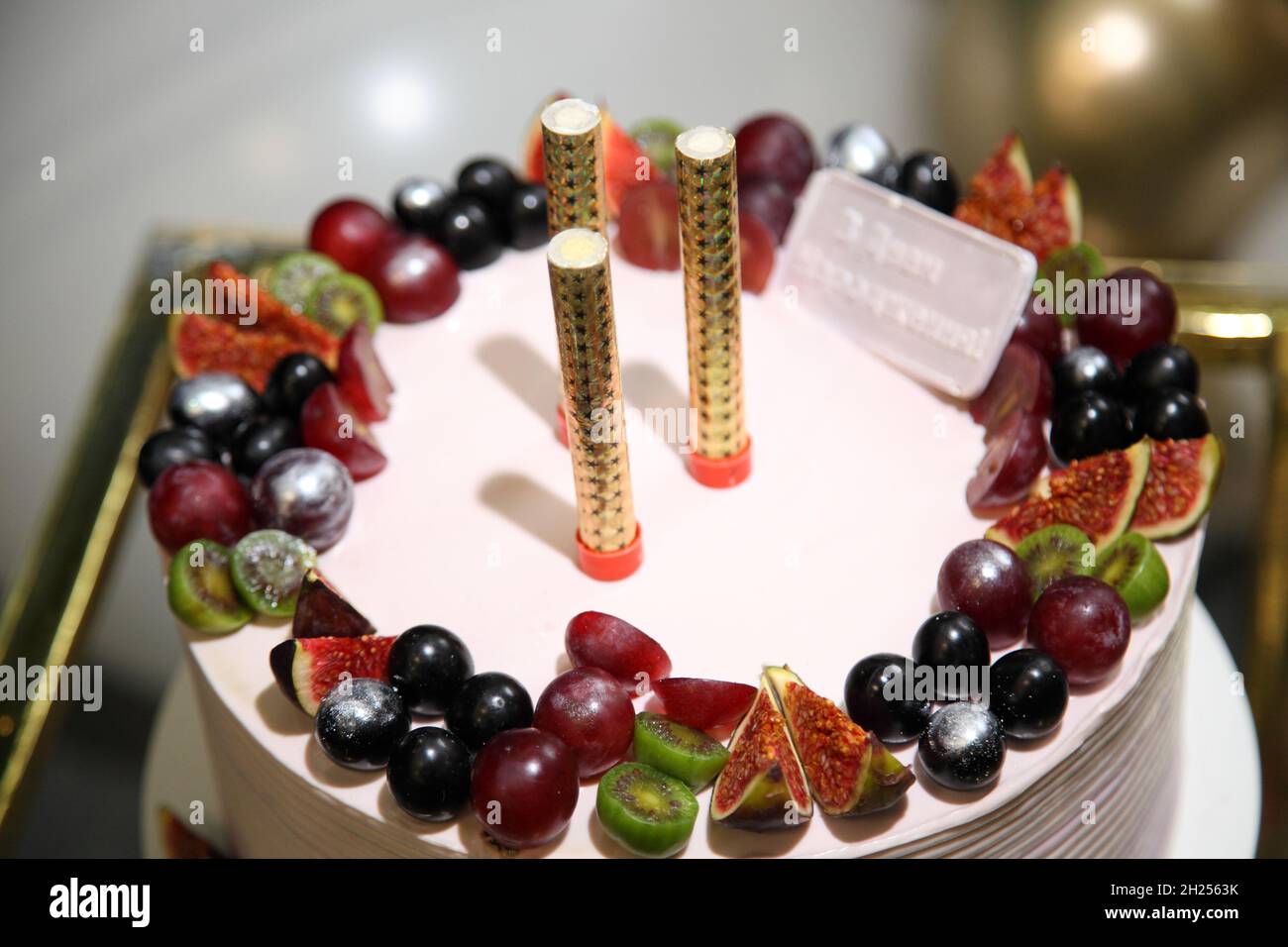 Geburtstagskuchen mit Dekorationen. Festlicher Kuchen mit Obst und einer Inschrift auf Ukrainisch „Happy Birthday!“ Stockfoto