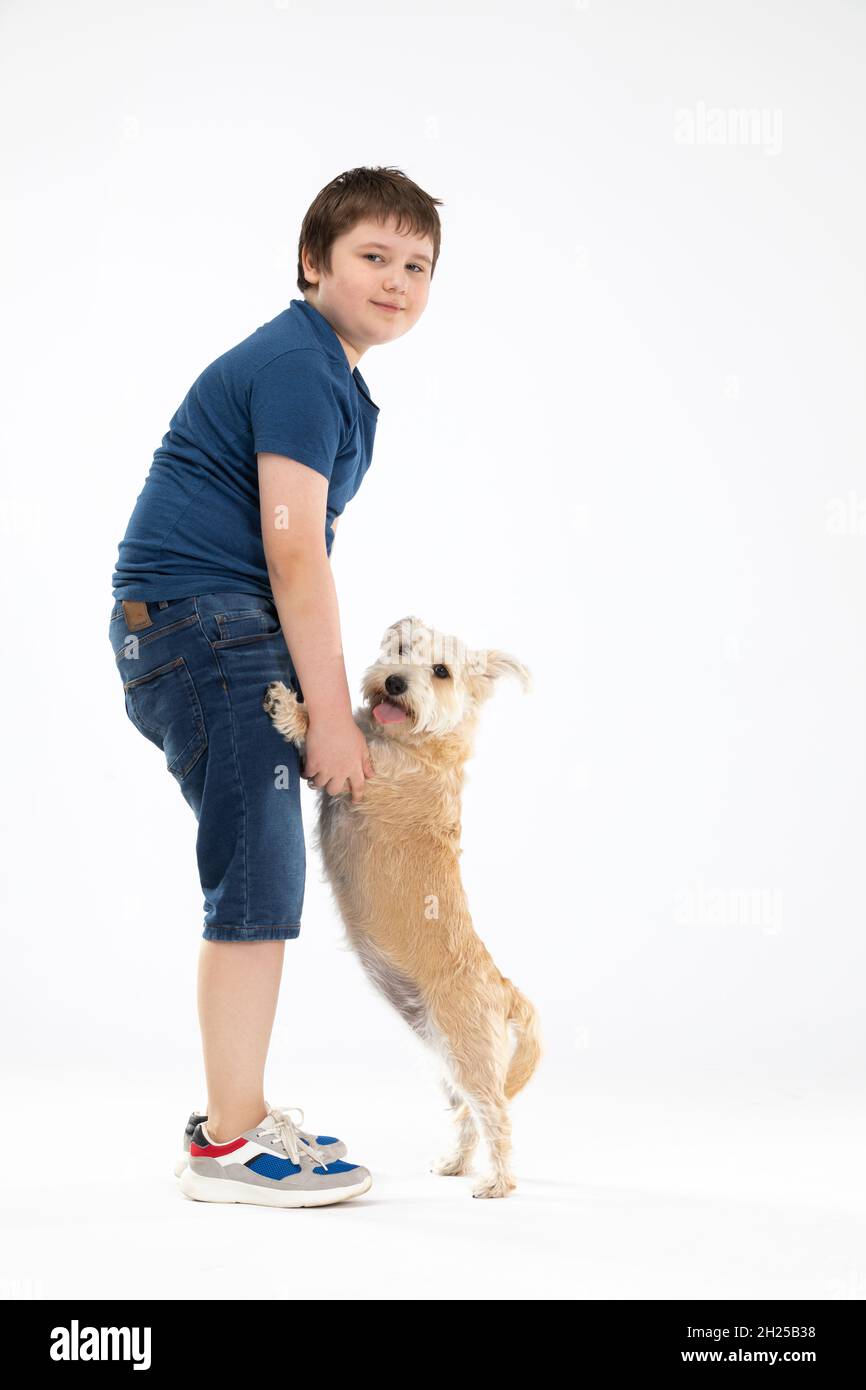 Der Hund steht auf seinen Hinterbeinen und der Junge hält ihn an seinen Vorderpfoten und beide blicken in die Kamera. Stockfoto