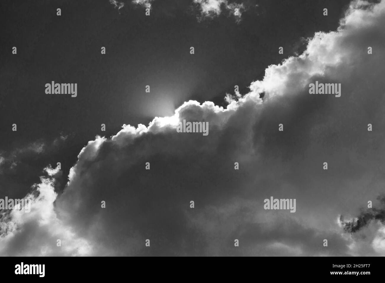 Sonne bricht durch die Cumuluswolke in einen strahlend blauen Himmel (schwarz und weiß) Stockfoto