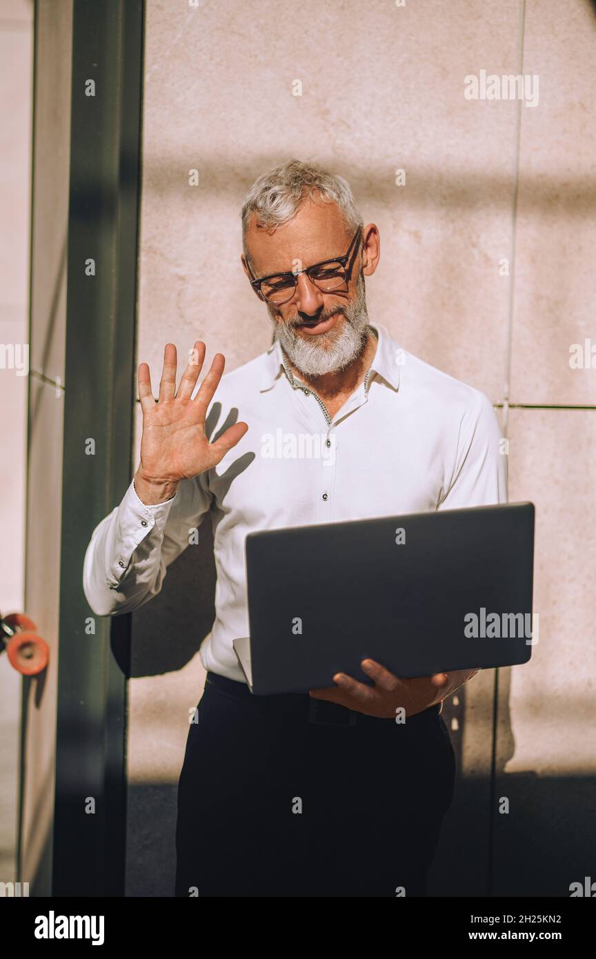 Reifer kaukasischer Mann, der mit seinen Kontakten über Skype kommuniziert Stockfoto