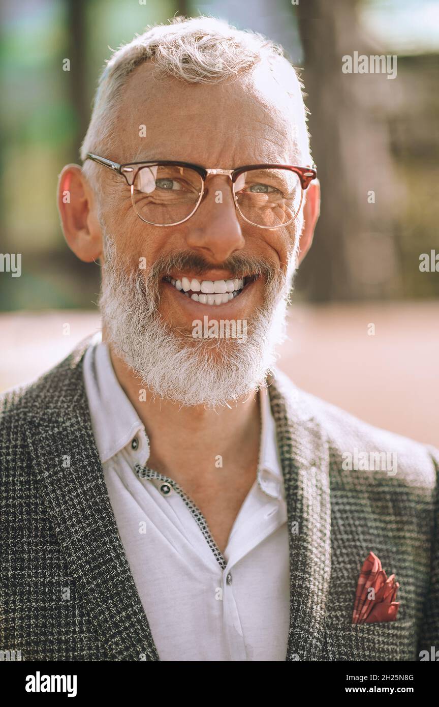 Fröhlicher, hübscher, stilvoller Mann, der die Kamera anlächelt Stockfoto