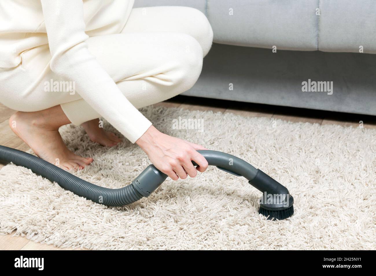 Frau saugt den Teppich im Schlafzimmer. Stockfoto