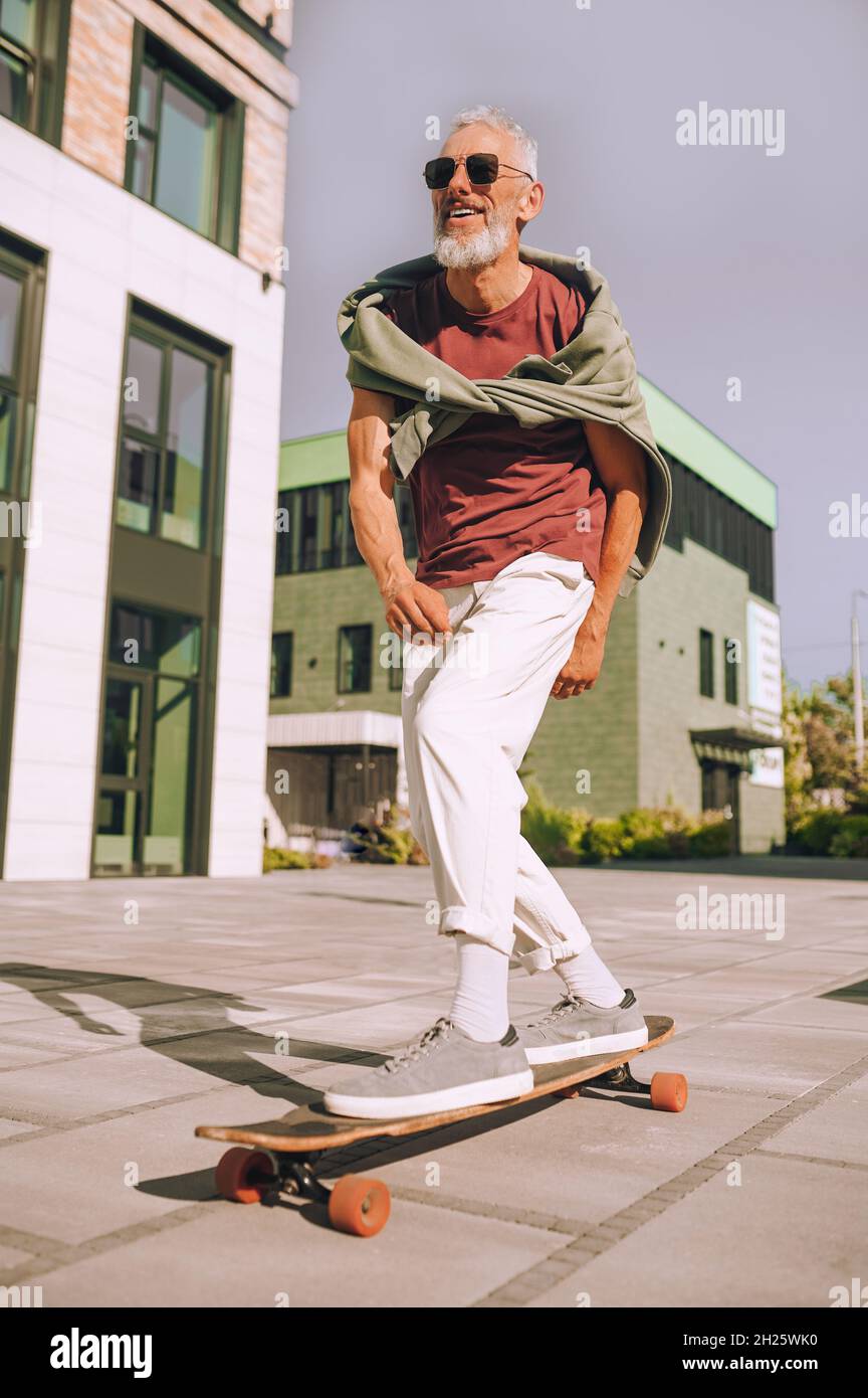 Energischer Mann, der mit seinen beiden Füßen auf dem Skateboard steht Stockfoto