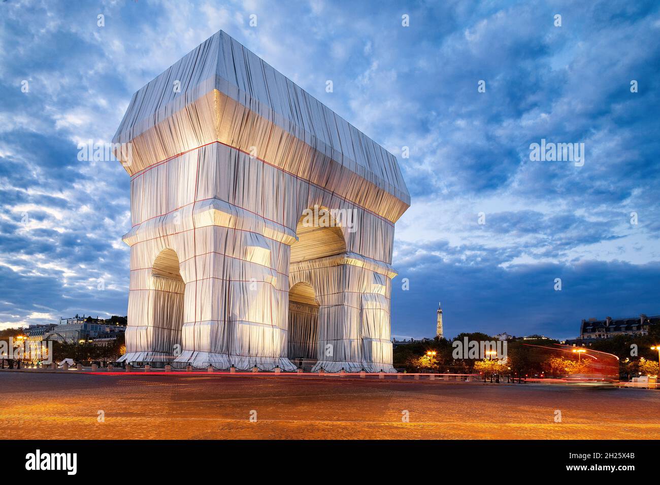 Der Arc de Triomphe von Paris wurde nach der Idee von Christo und Jeanne-Claude mit dem Eiffelturm im Hintergrund gewickelt. Stockfoto