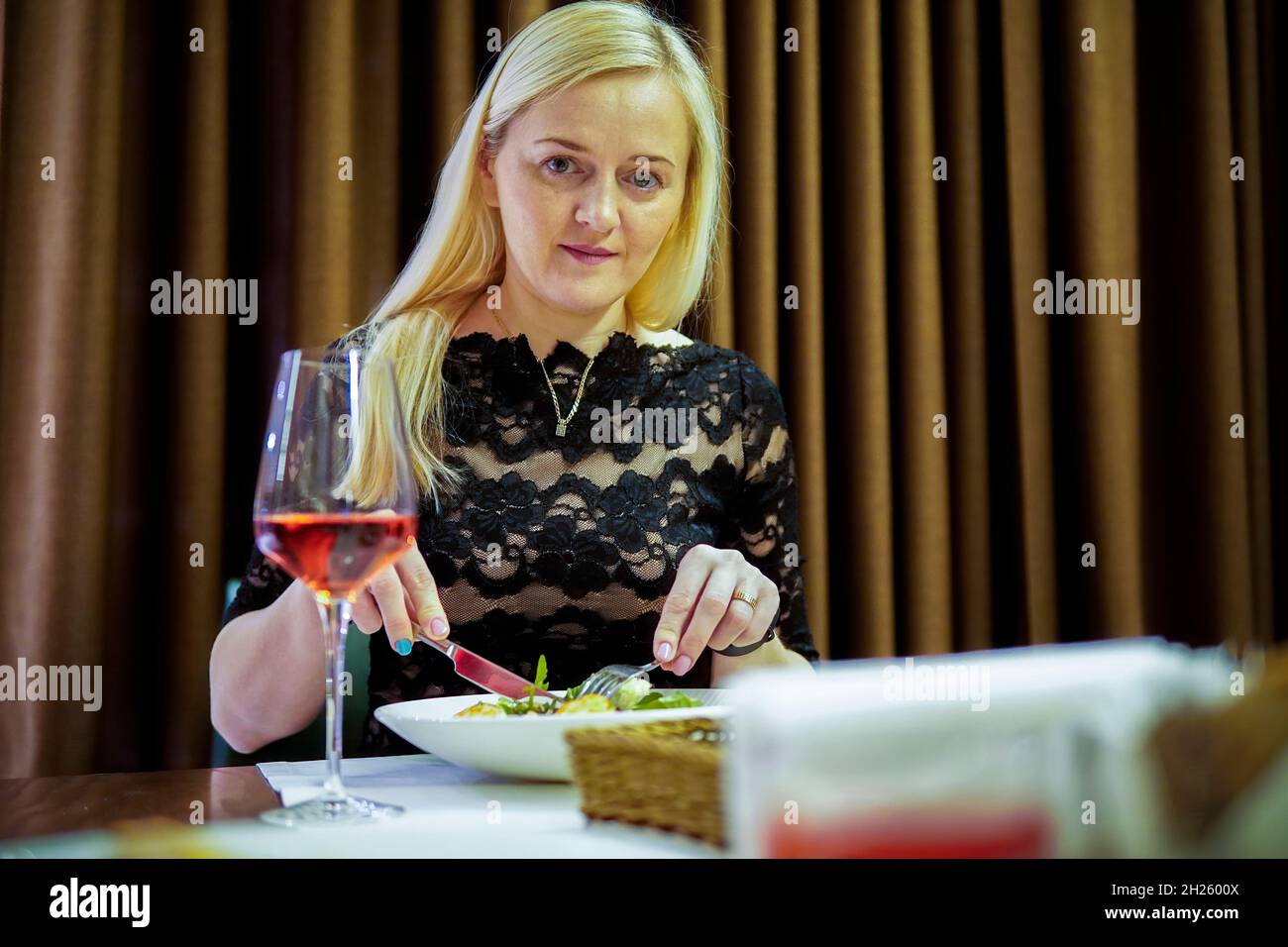 Blonde Frau, die in einem Restaurant zu Abend gegessen hat und mit einem Glas Wein gefällig war Stockfoto