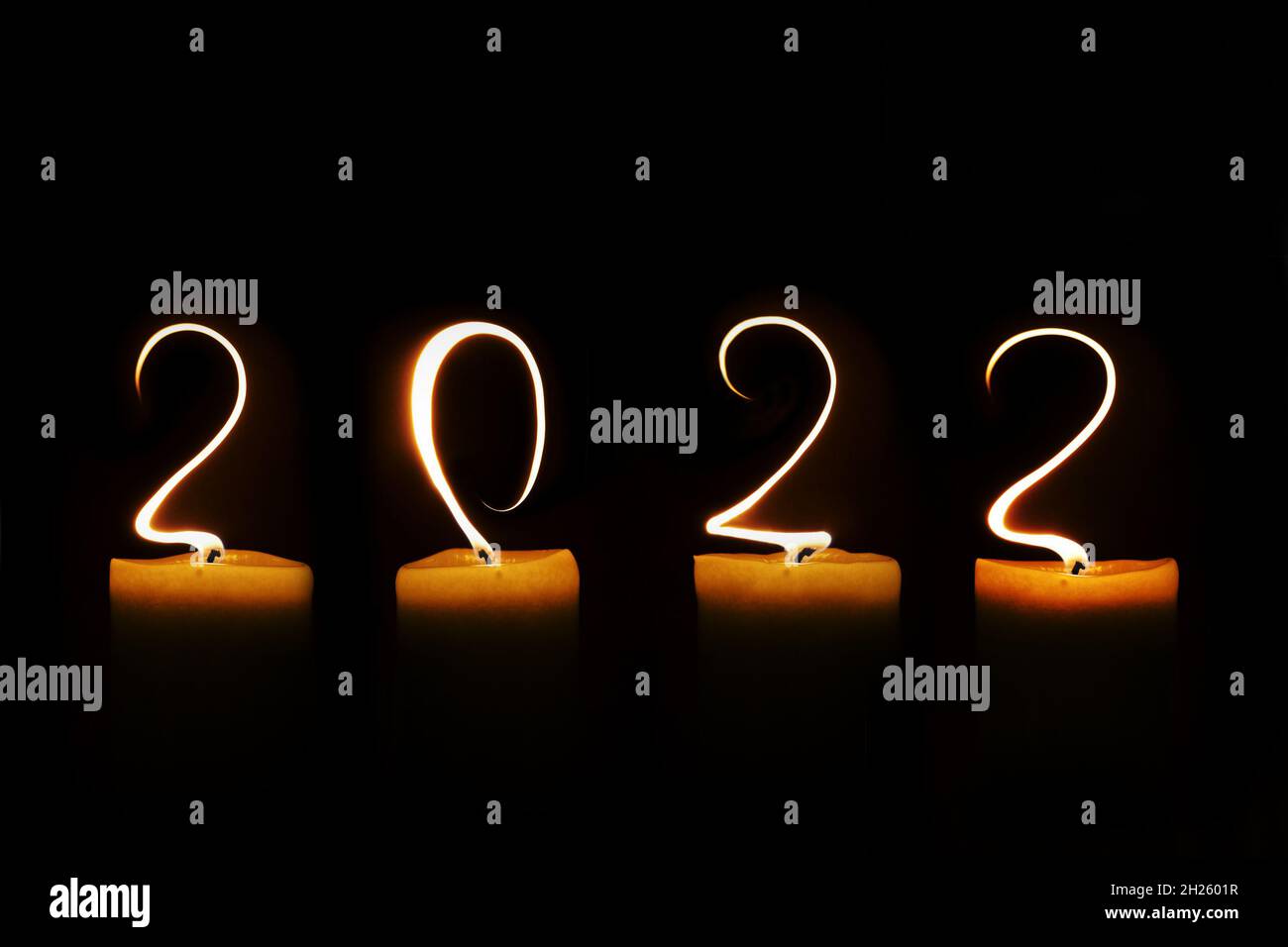 2022 geschrieben mit Kerzenflammen auf schwarzem Hintergrund, Neujahr Grußkarte Stockfoto