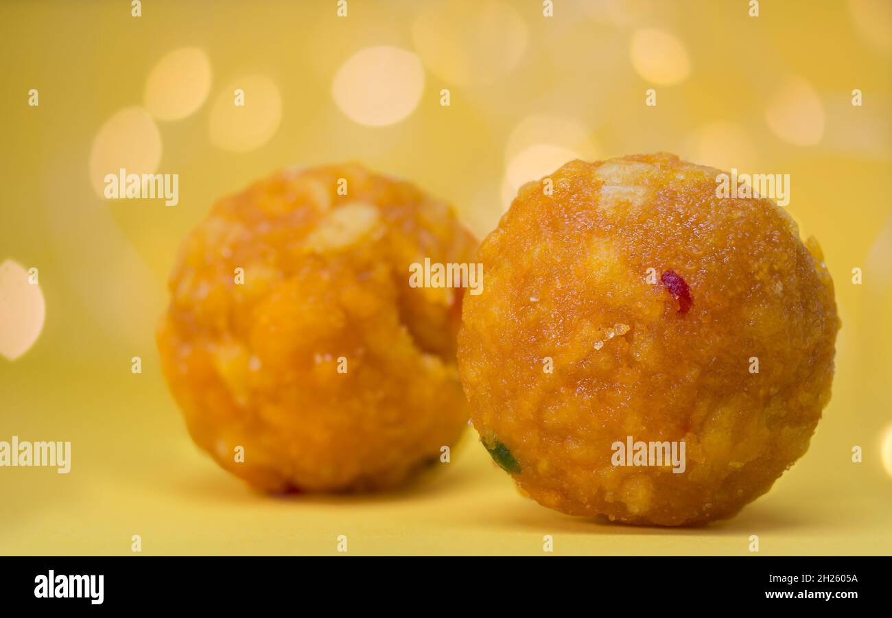 Kugelförmige Süßigkeiten, bekannt als Laddu oder Laddoo, beliebtes zuckerhaltiges Essen auf indischen Festivals, Nahaufnahme im dekorierten Hintergrund Stockfoto
