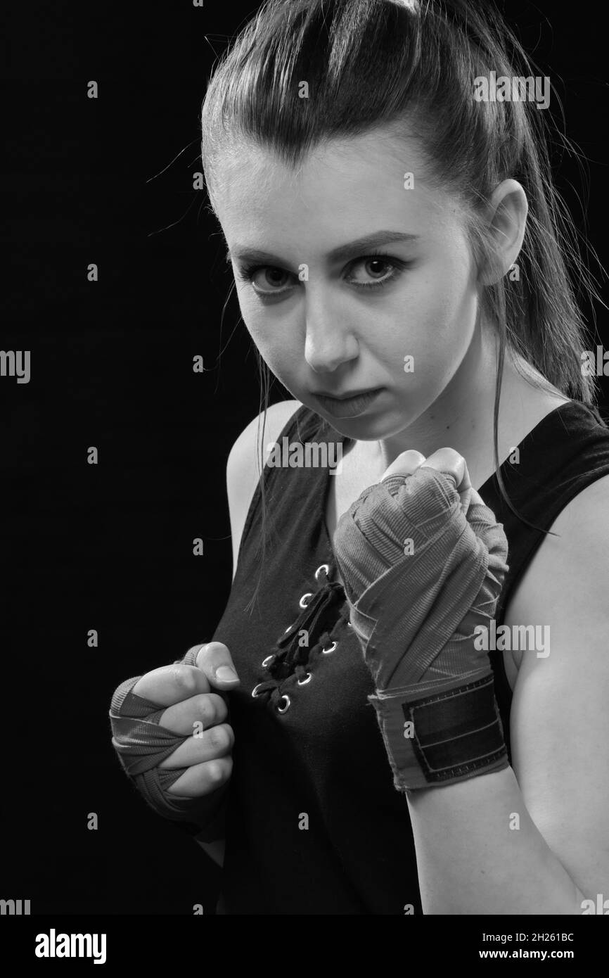 Muay Thai Boxerin in Angriffsstellung. Fitness junge Frau Boxtraining auf schwarzem Hintergrund, monochrom Stockfoto