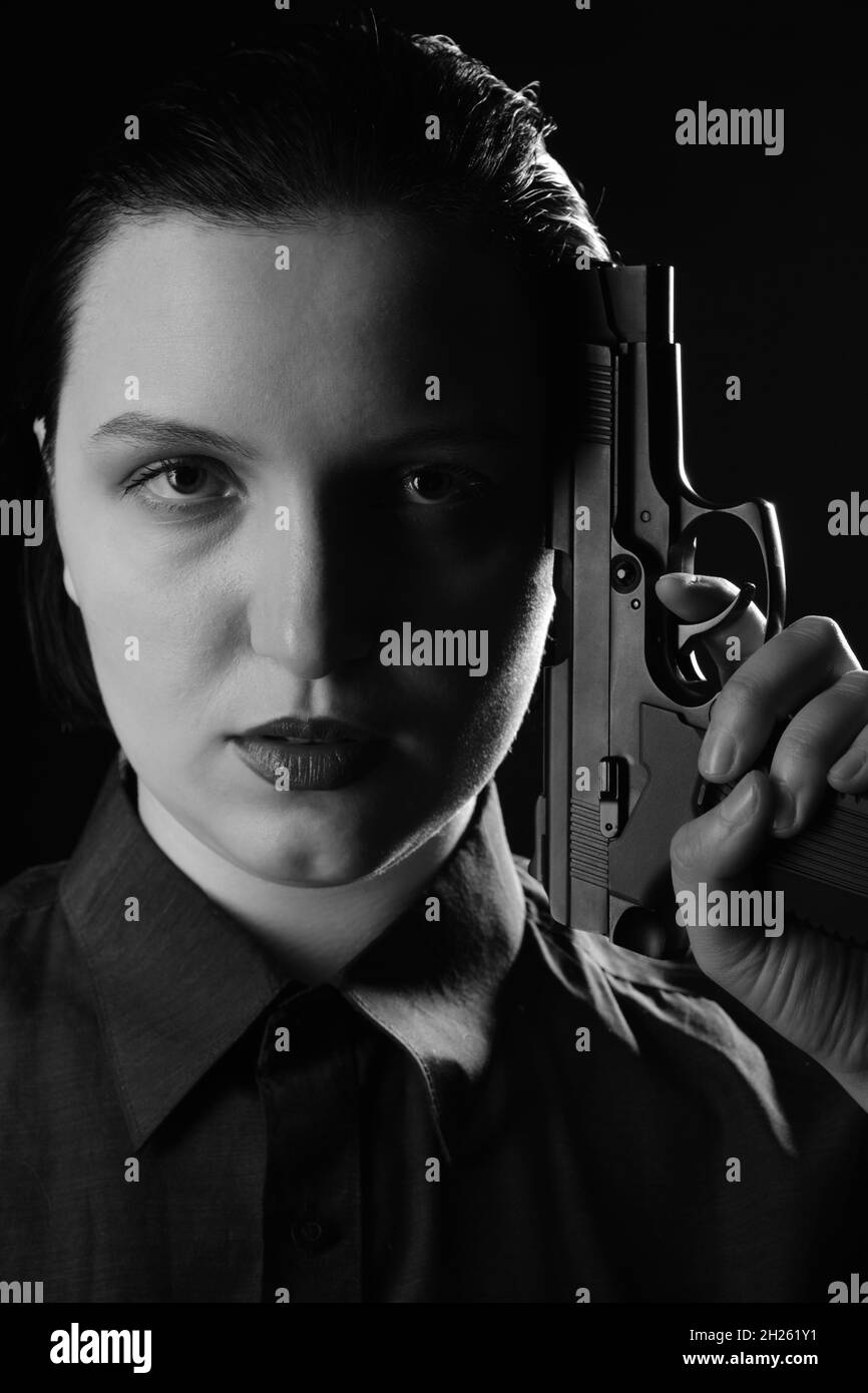Weibliche Porträt mit Pistole Nahaufnahme auf schwarzem Hintergrund Seitenansicht Stockfoto