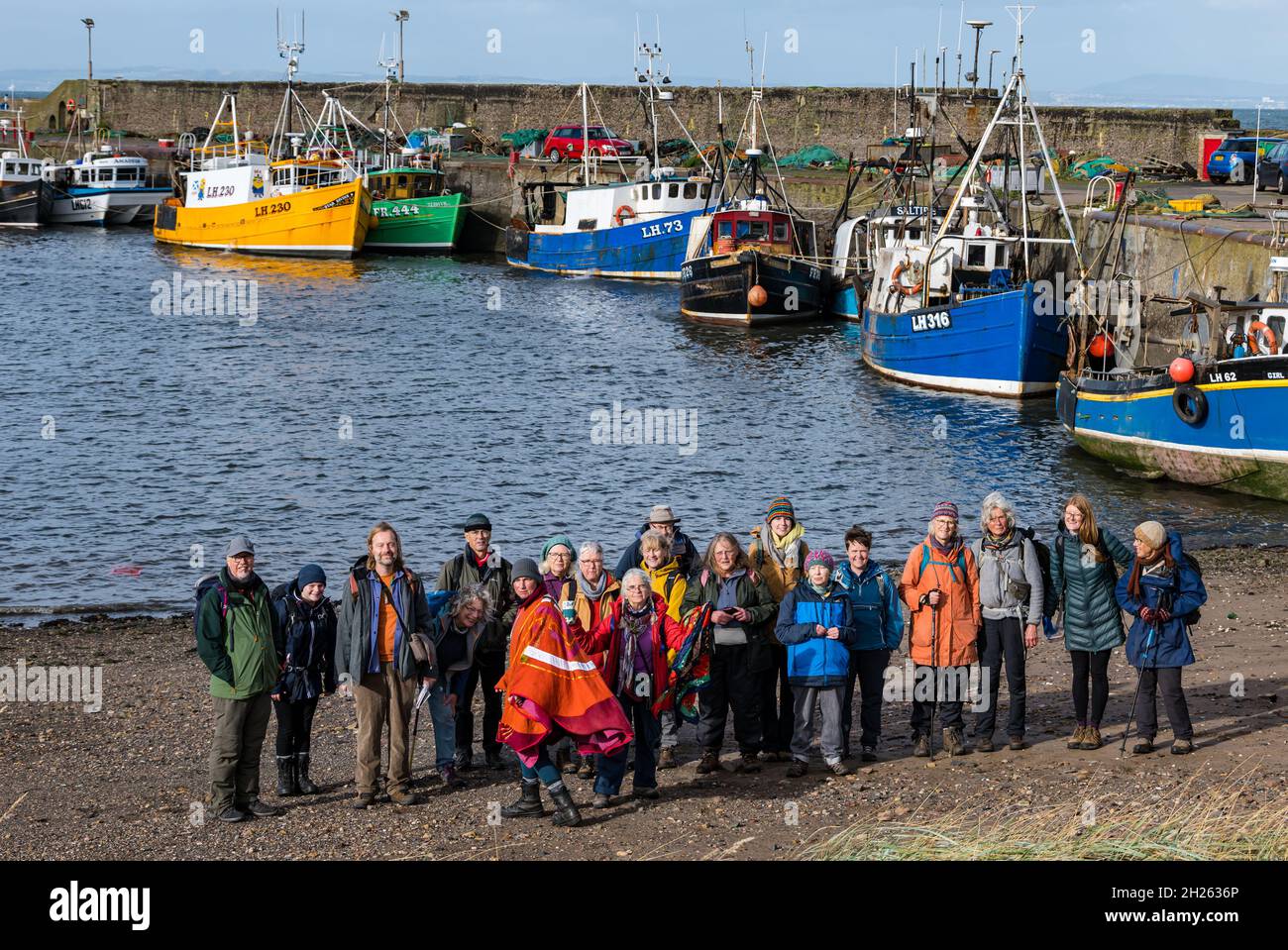 East Lothian, Schottland, Großbritannien, 20. Oktober 2021. COP26 Pilgerfahrt: Basisgruppen auf der schottischen Etappe eines Spaziergangs zur COP26. Die Teilnehmer, die sich auf dem Weg anschließen, glauben, dass die COP26 nicht die wesentlichen Veränderungen herbeiführen wird, die zur Bekämpfung des Klimawandels erforderlich sind. Die Route heute ist auf dem John Muir Way. Im Bild: Die Gruppe am Hafen von Port Seton mit Fischerbooten, die bei Ebbe auf Grund liegen Stockfoto