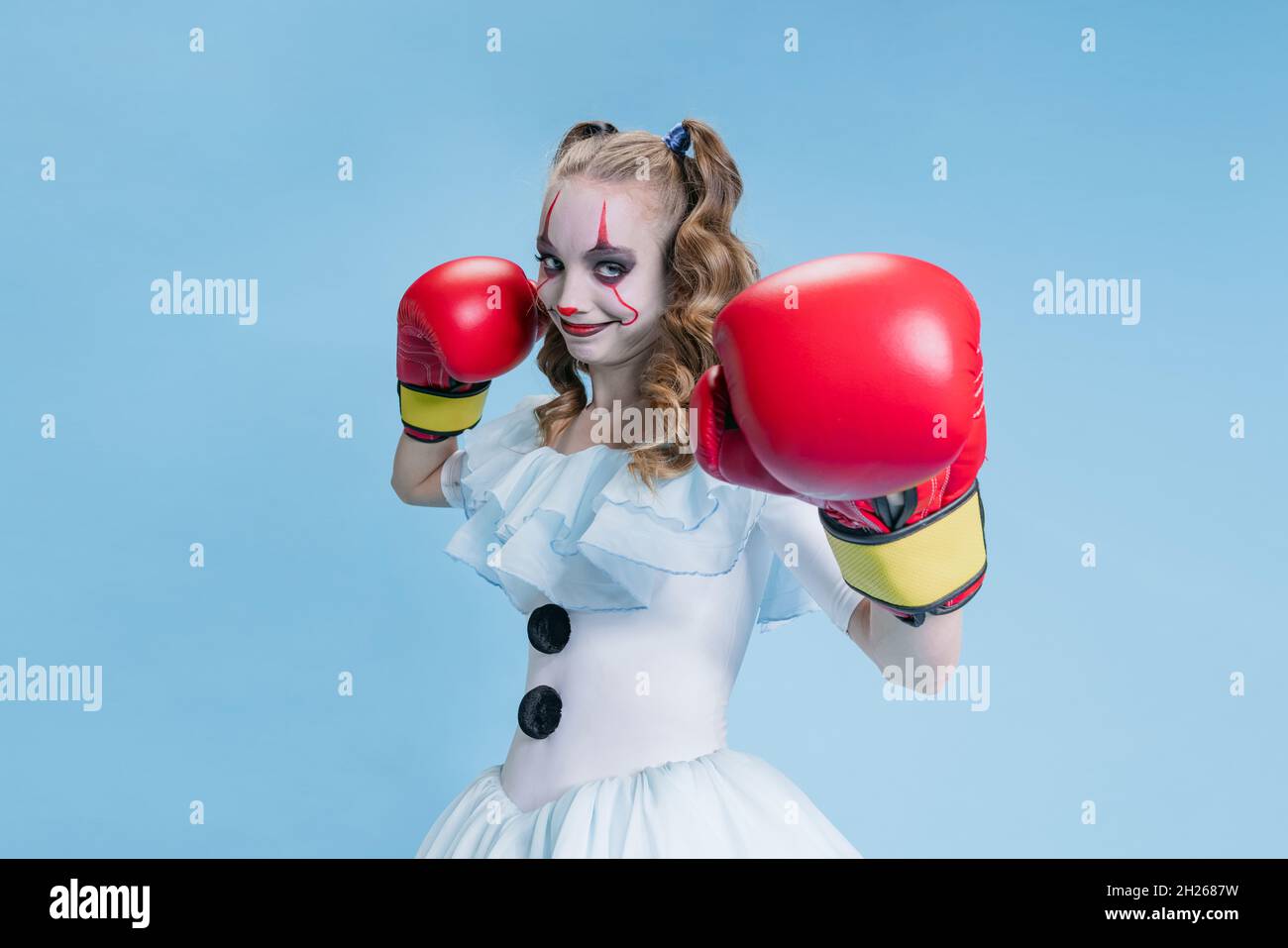 Portrait eines charismatischen jungen Mädchens in Halloween Kostüm von Filmcharakter mit gruseligen Gesichtsausdruck isoliert auf blauem Hintergrund Stockfoto