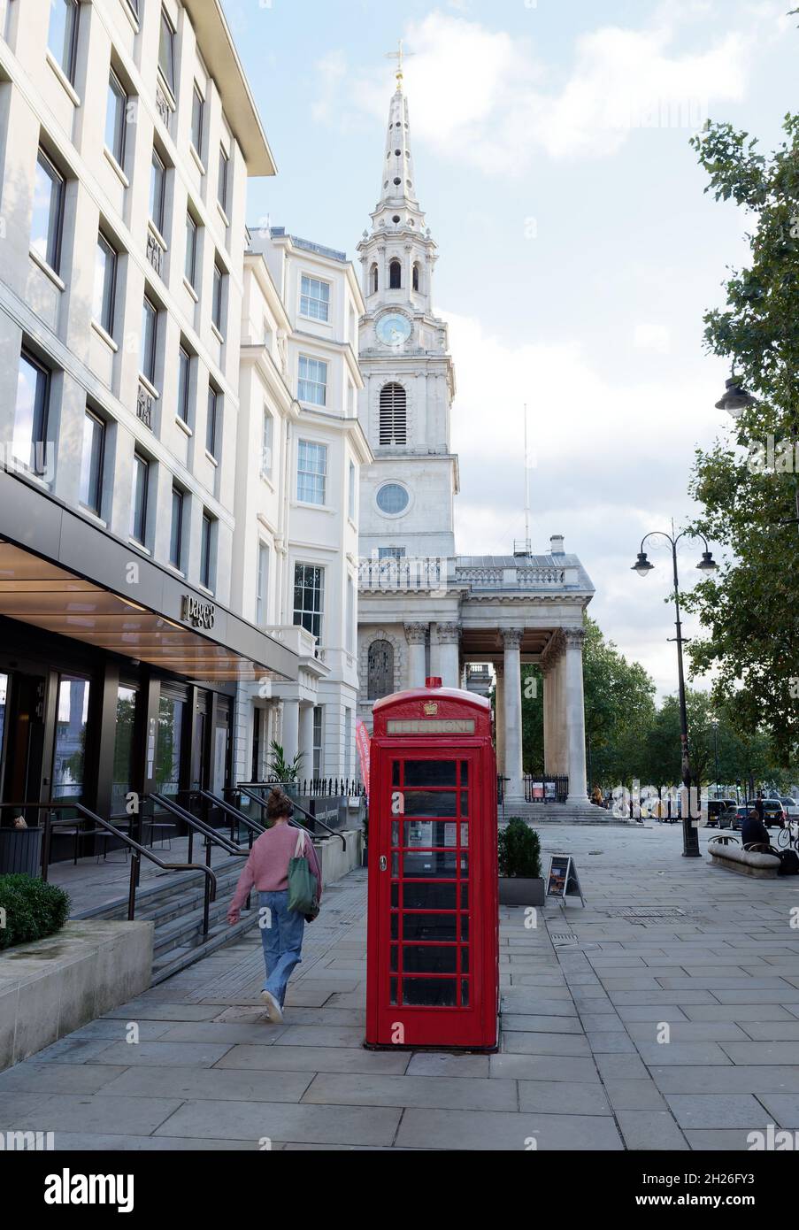 London, Greater London, England, Oktober 05 2021: Rote Telefondose mit St. Martin in der Kirche Fields hinter dem Trafalgar Square. Stockfoto