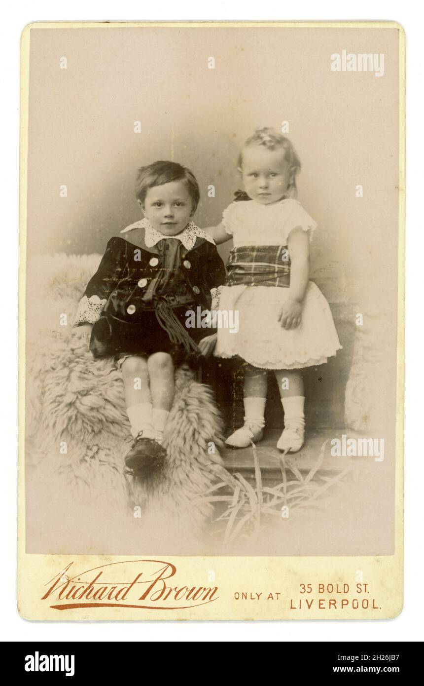 Viktorianische Kabinettkarte von 2 Kindern, Bruder und Schwester, trägt der Junge eine Samtjacke im Little Lord Fauntleroy-Stil mit Spitzenkragen. Aus dem Studio von Richard Brown, Liverpool, England, um 1895 Stockfoto