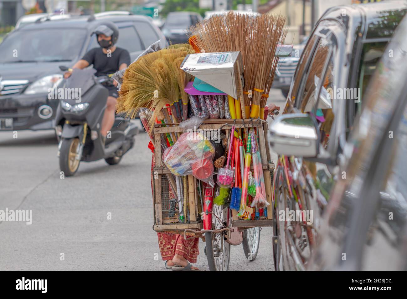 Eine Frau, die Reinigungs- und Haushaltsgegenstände verkauft, benutzt ein Fahrrad als Transportmittel. BOYOLALI, INDONESIEN - 18. OKTOBER 2021. Stockfoto