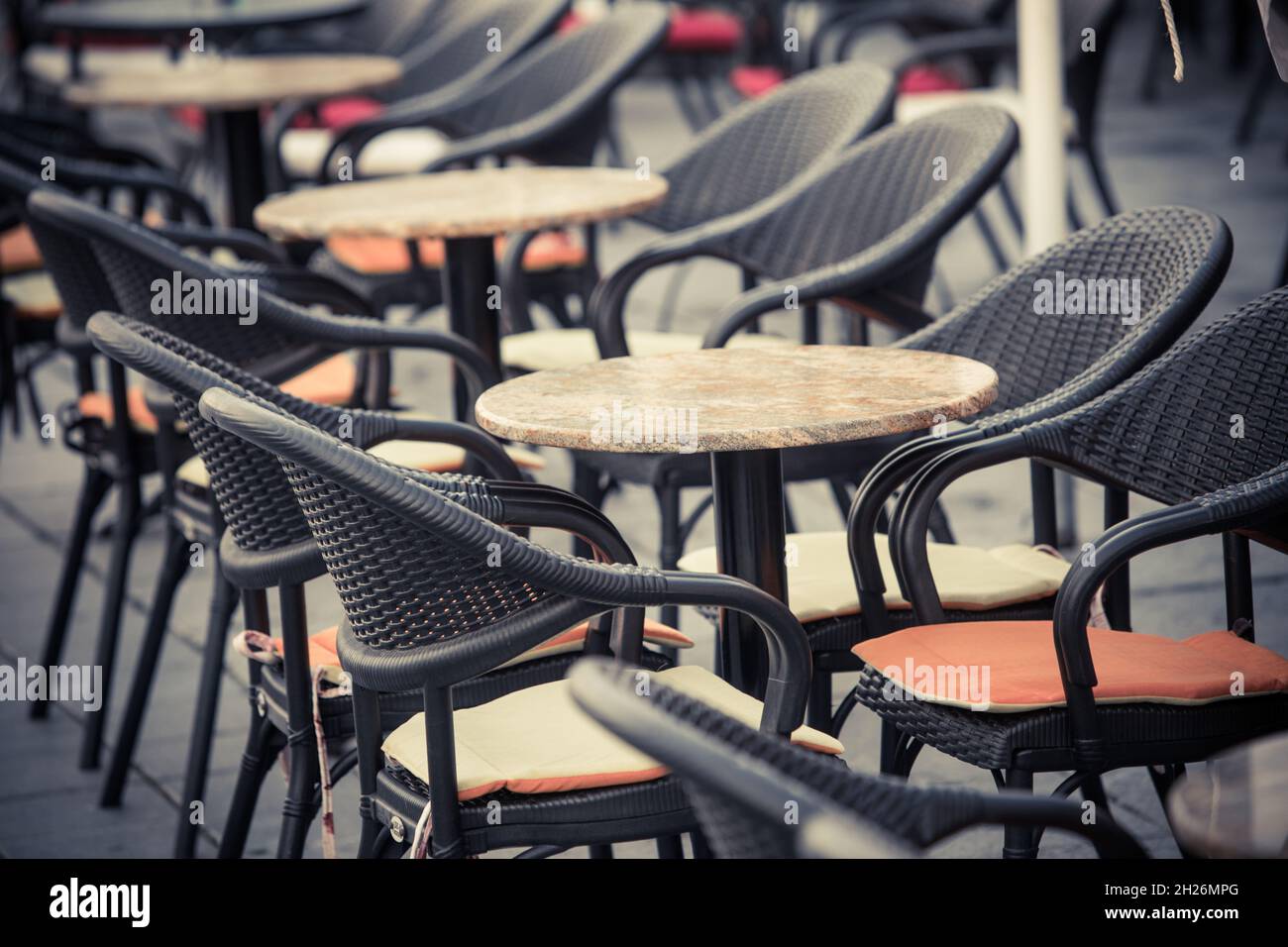 Farbbild leerer Stühle und Tische auf einer Freiluftterrasse. Stockfoto