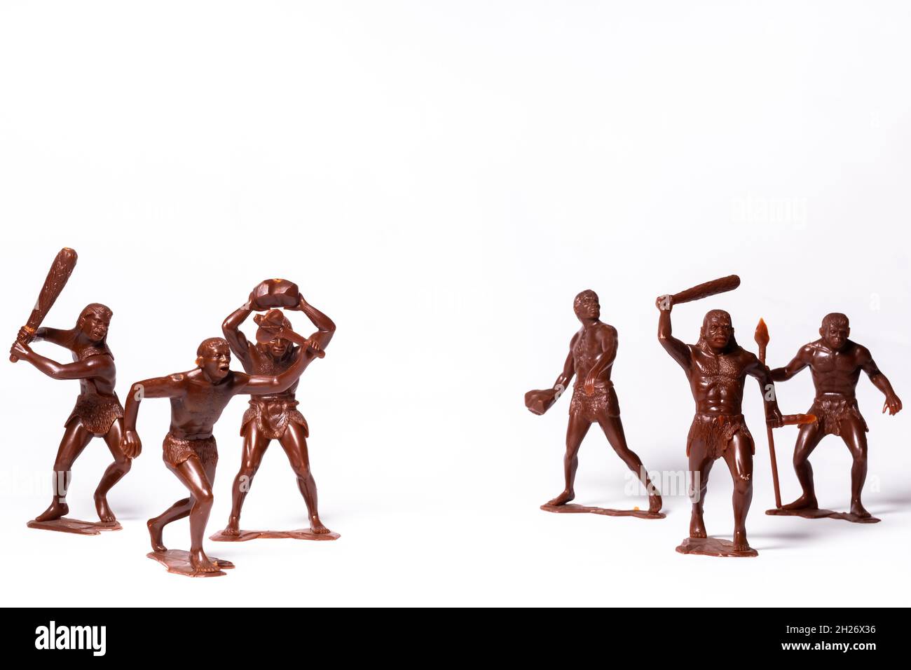 Große Spielzeugfiguren von primitiven Menschen auf weißem Hintergrund Stockfoto