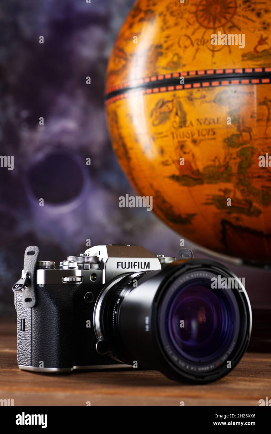 MINSK, WEISSRUSSLAND - 16. OKTOBER 2021: FUJIFILM X-T4 KIT XF16-80MM SILBERNES Kameragehäuse auf braunem Holzhintergrund mit einem Vintage-Globus im Hintergrund. Stockfoto