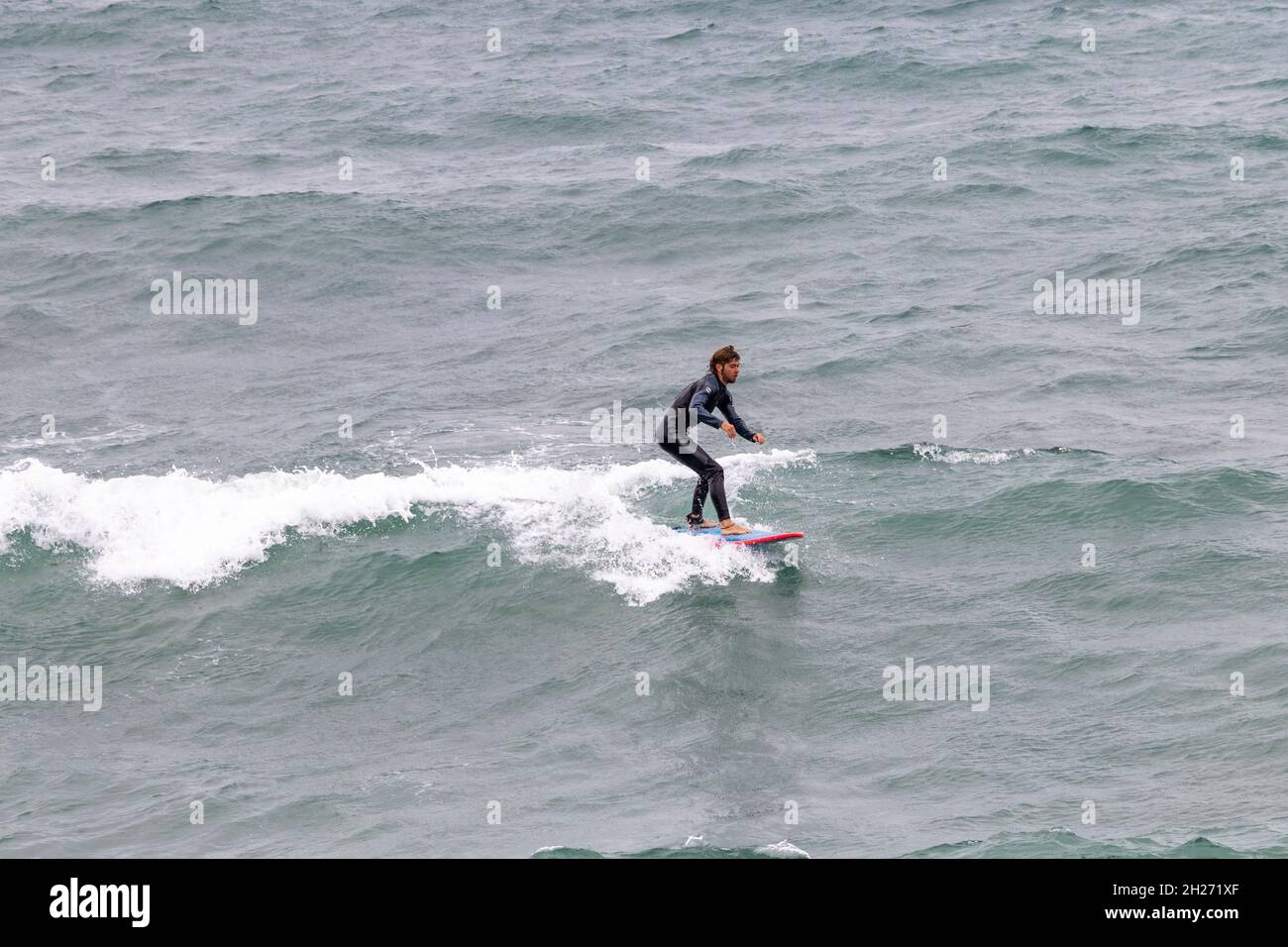 Barcelona, Spanien - 24. September 2021: Wetsuit Surfer fangen eine Welle Stockfoto