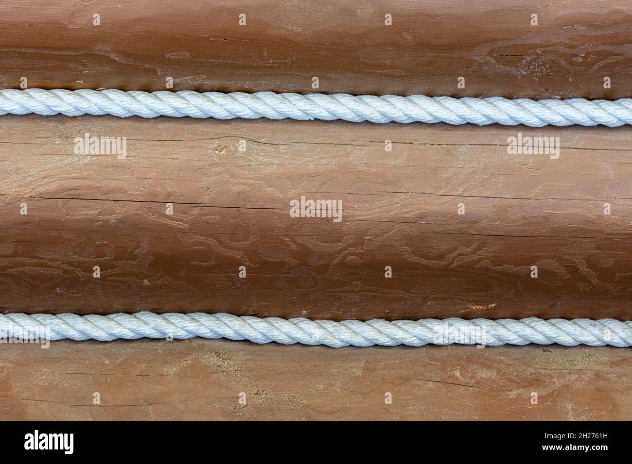 Wand aus braun gemalten Baumstämmen mit weißen geflochtenen Seilen für den Einsatz als abstrakte Hintergründe und Texturen verziert. Stockfoto