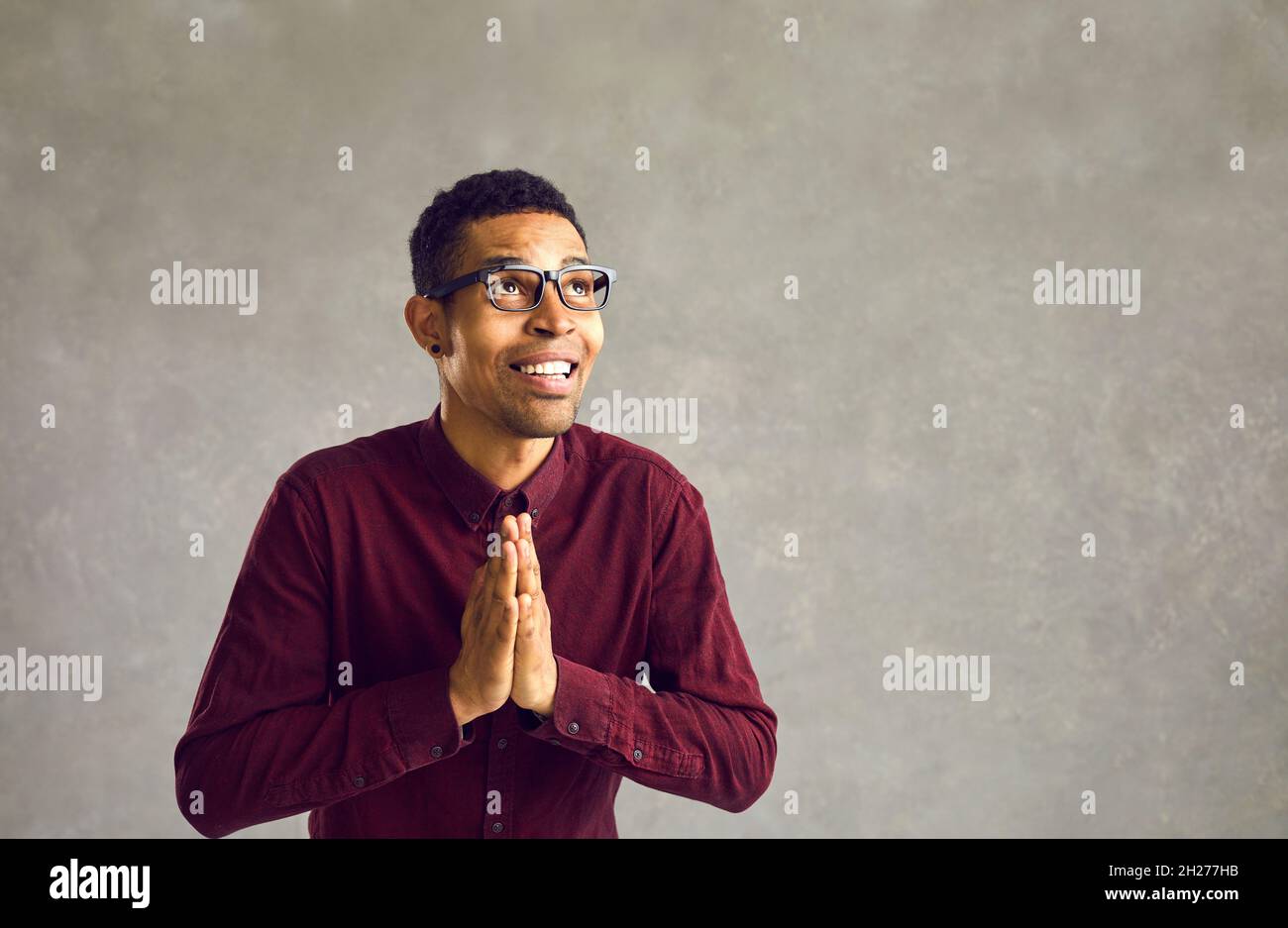 Dankbarer afroamerikanischer Mann, der mit den Händen betet und im Studio aufschaut Stockfoto