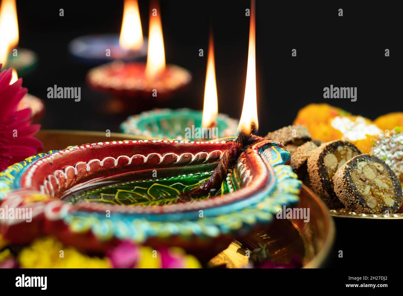 Detaillierte Nahaufnahme Von Großen Bunten Ton Diya Tief Oder Dia Öl-Lampen In Verzierten Messing Thali Glühend In Dunkel. Thema Für Diwali Pooja, Navratri, Happy New Stockfoto