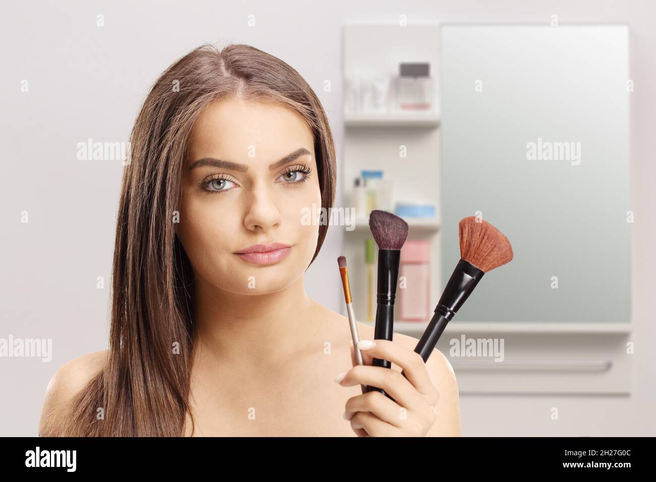 Schöne junge Frau hält Make-up Bürsten im Badezimmer Stockfoto