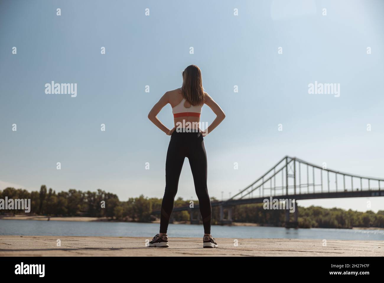 Schlanke Frau in Sportbekleidung mit Händen auf dem Damm steht Stockfoto
