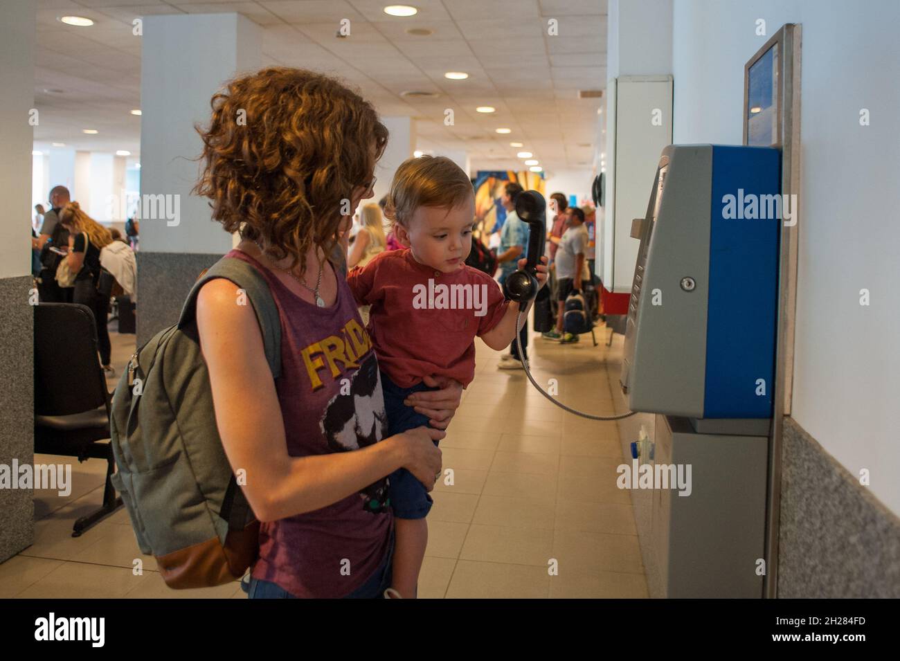 MAR DEL PLATA, ARGENTINIEN - 28. Dez 2017: Eine Mutter hält ihren Sohn vor einem öffentlichen Telefon im Flughafen Astor Piazzolla in Mar del Plata, Argent Stockfoto