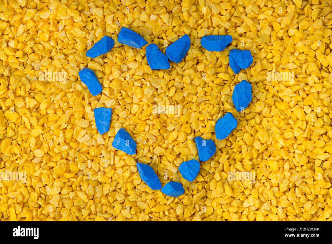 Kieselsteine in Form von Blue Heart auf gelbem Hintergrund, Valentinstag-Konzept. Symbol der Liebe in den Farben der Nationalflagge der Ukraine Stockfoto