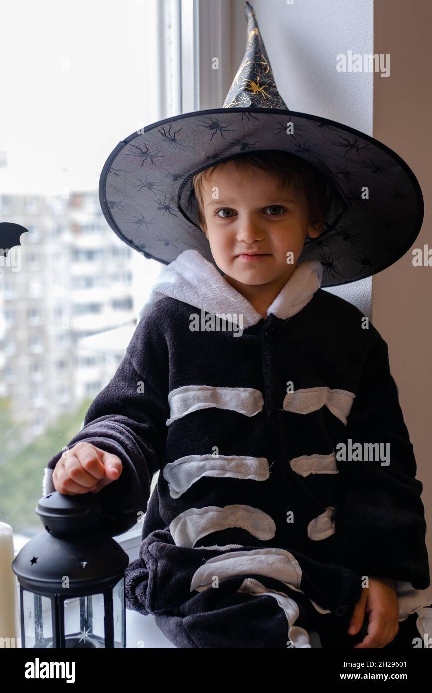 Ein Kleiner Junge Im Skelett Kostum Und Hexenhut Fur Halloween Sitzt Am Fenster Und Lachend Stockfotografie Alamy