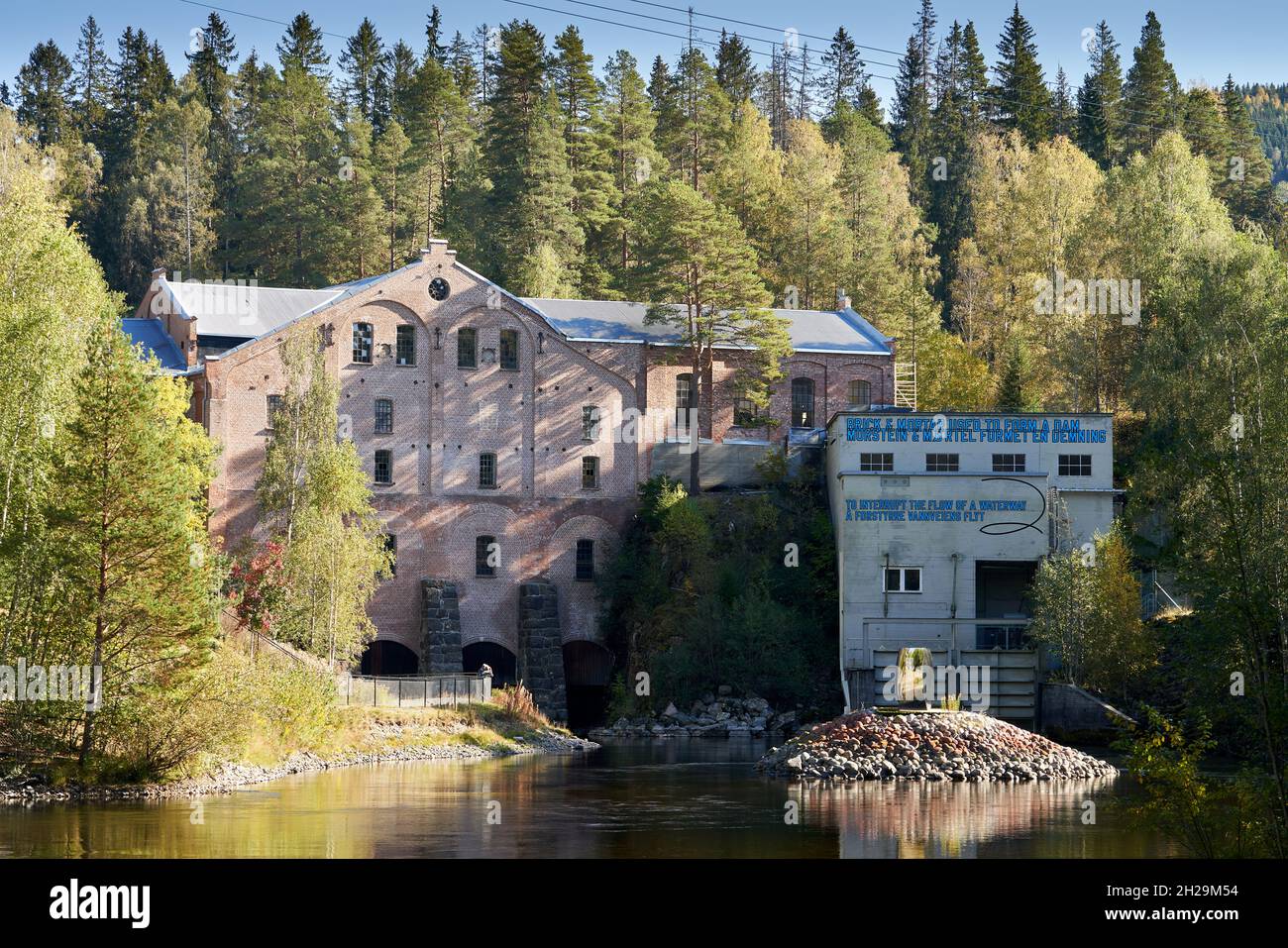JEVNAKER, NORWEGEN - 25. Sep 2021: Das Industriemuseum der Kistefos Holzscheibmühle an einem von Bäumen umgebenen Flussufer in Jevnaker, Norwegen Stockfoto