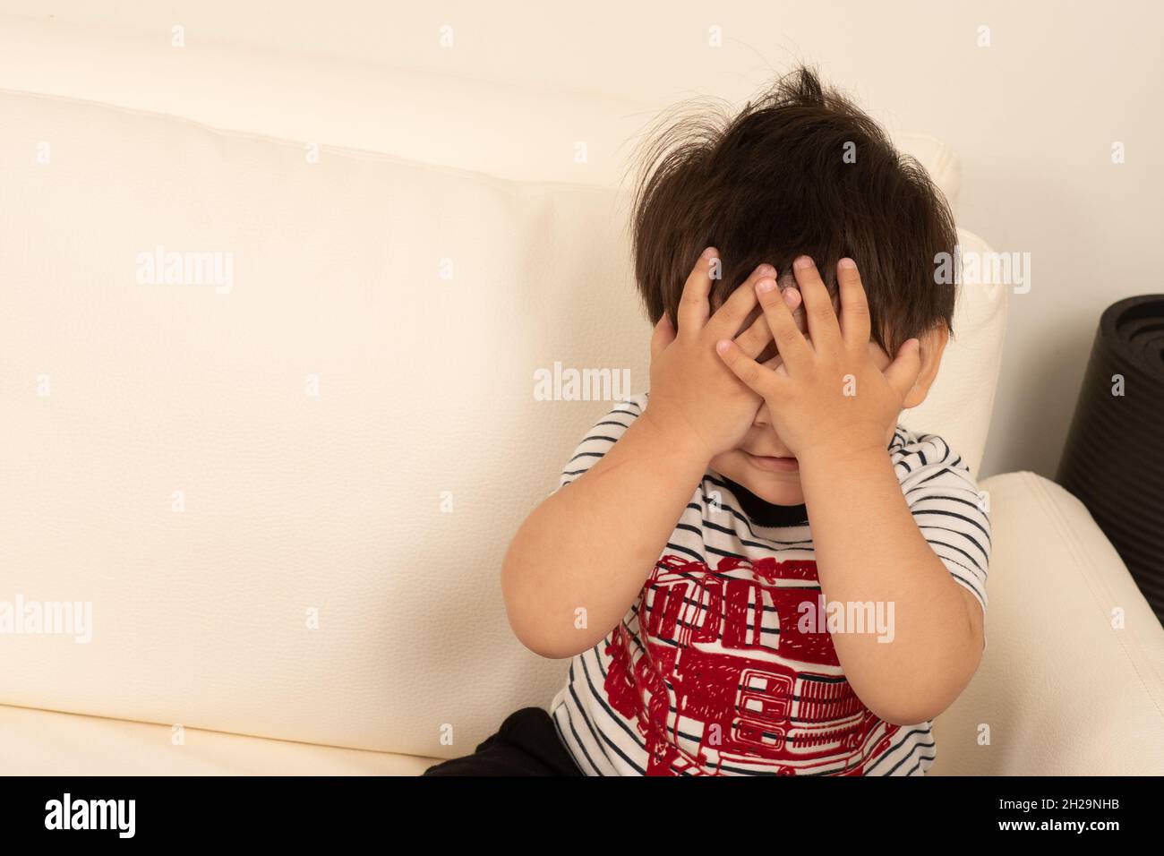 1 von 2 zweijährigen Jungen, der sich hinter seinen Händen versteckt, gucken einen Buh Stockfoto
