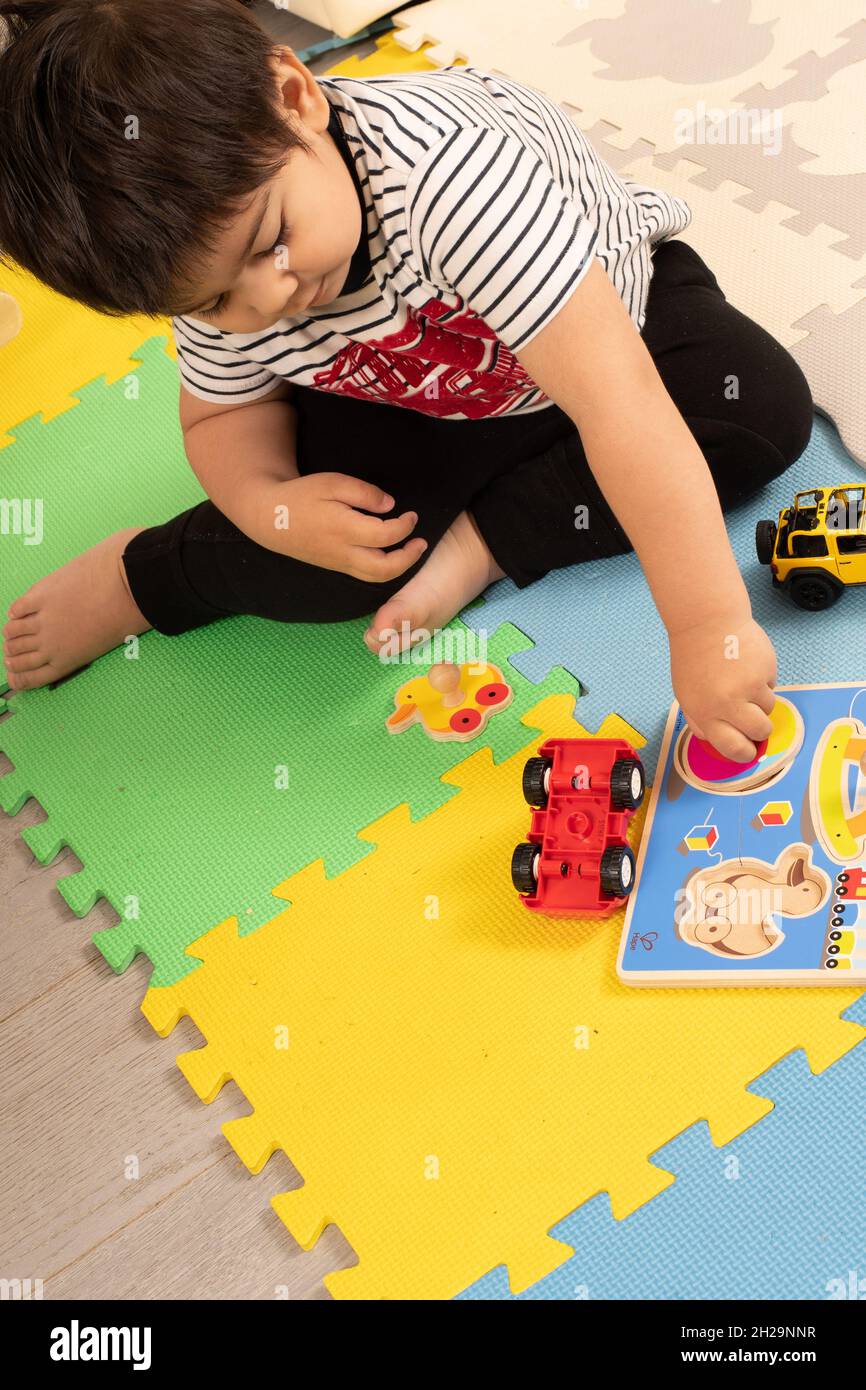 2-jähriger Kleinkind Junge zu Hause Drehen Puzzle Stück in den Raum passen rotierenden Handgelenk Stockfoto